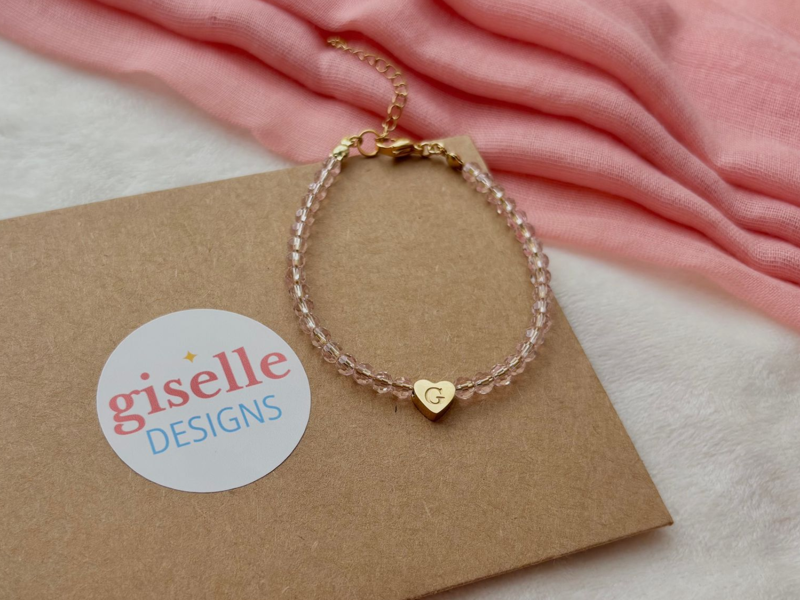 Pink beaded bracelet with a gold heart charm and the letter 