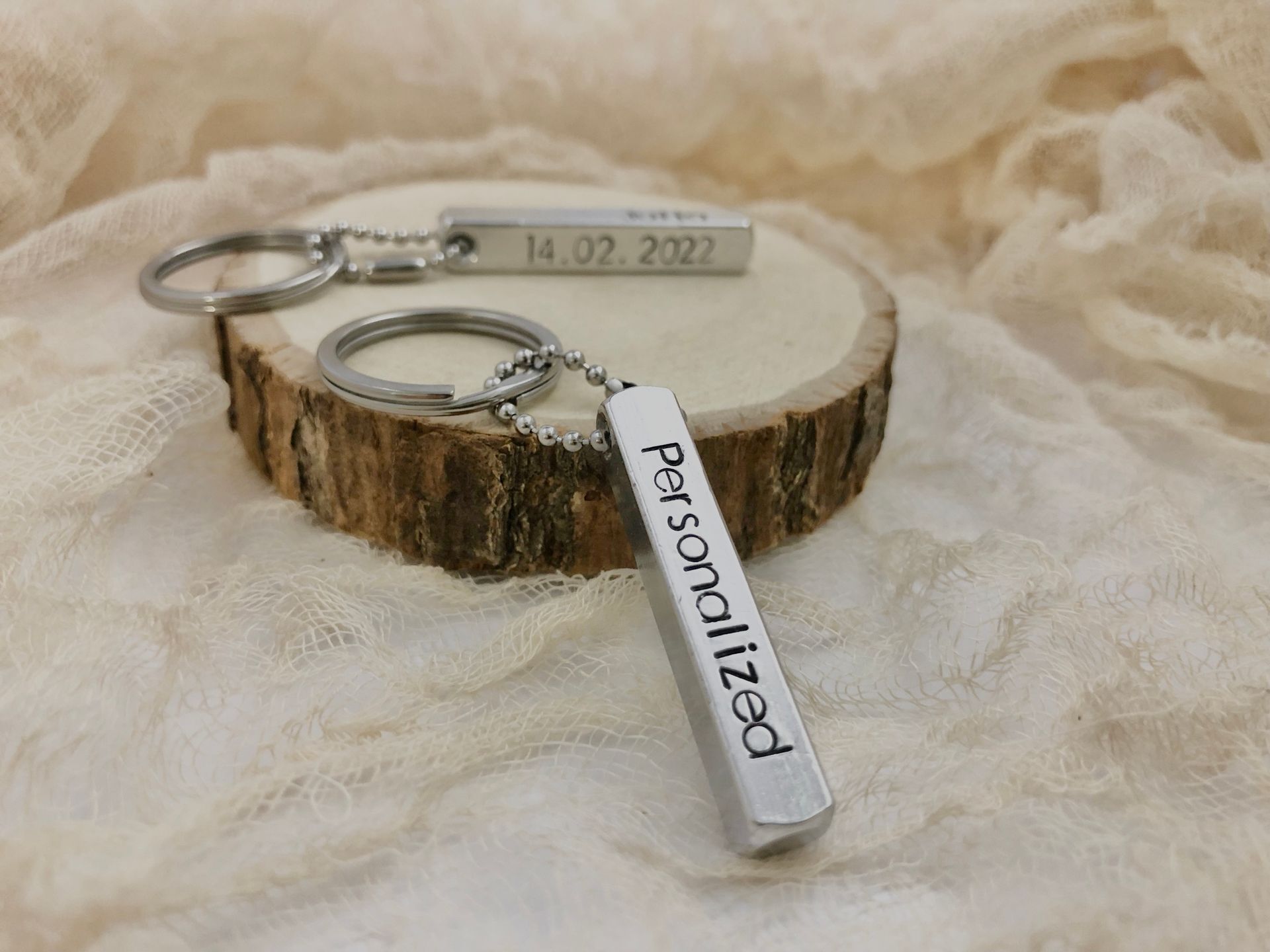 Two personalized keychains on a wooden slice. One says 