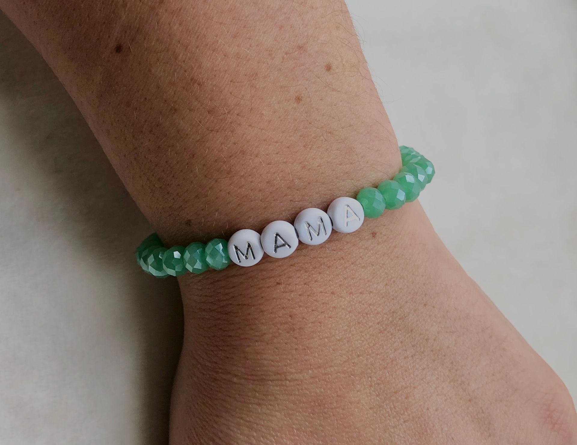 Hand holding three bracelets that spell 