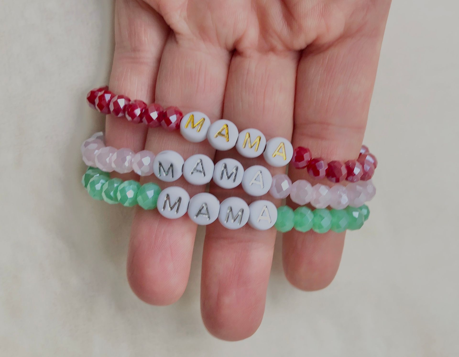Hand holding three bracelets that spell 