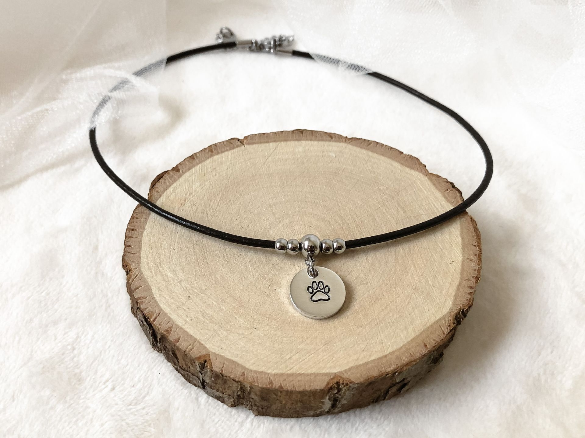 A hand holding a silver bracelet with a round charm displaying a zodiac symbol.