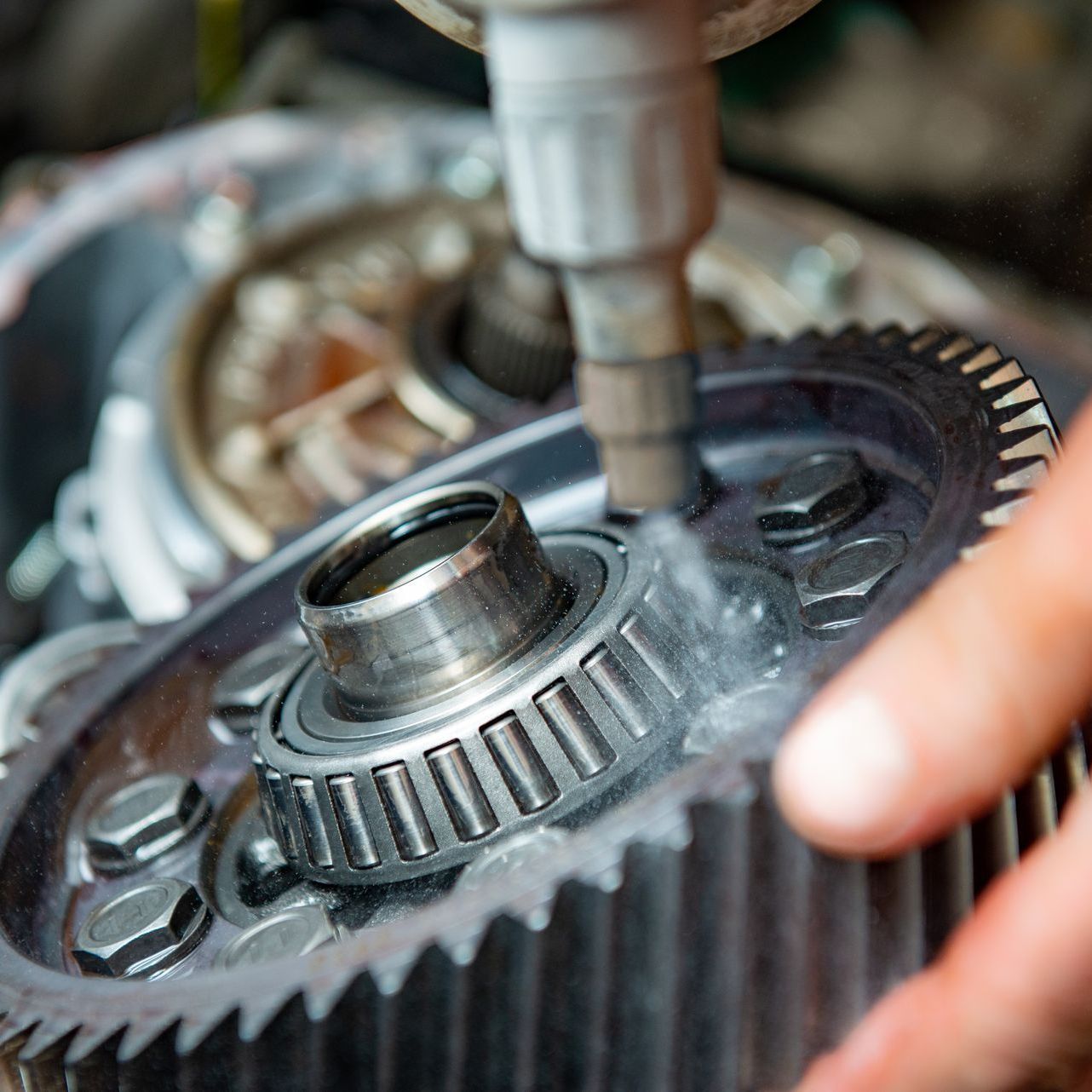 A close up of a person holding a gear in their hand.