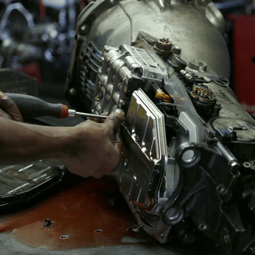 A person is working on a car engine with a screwdriver