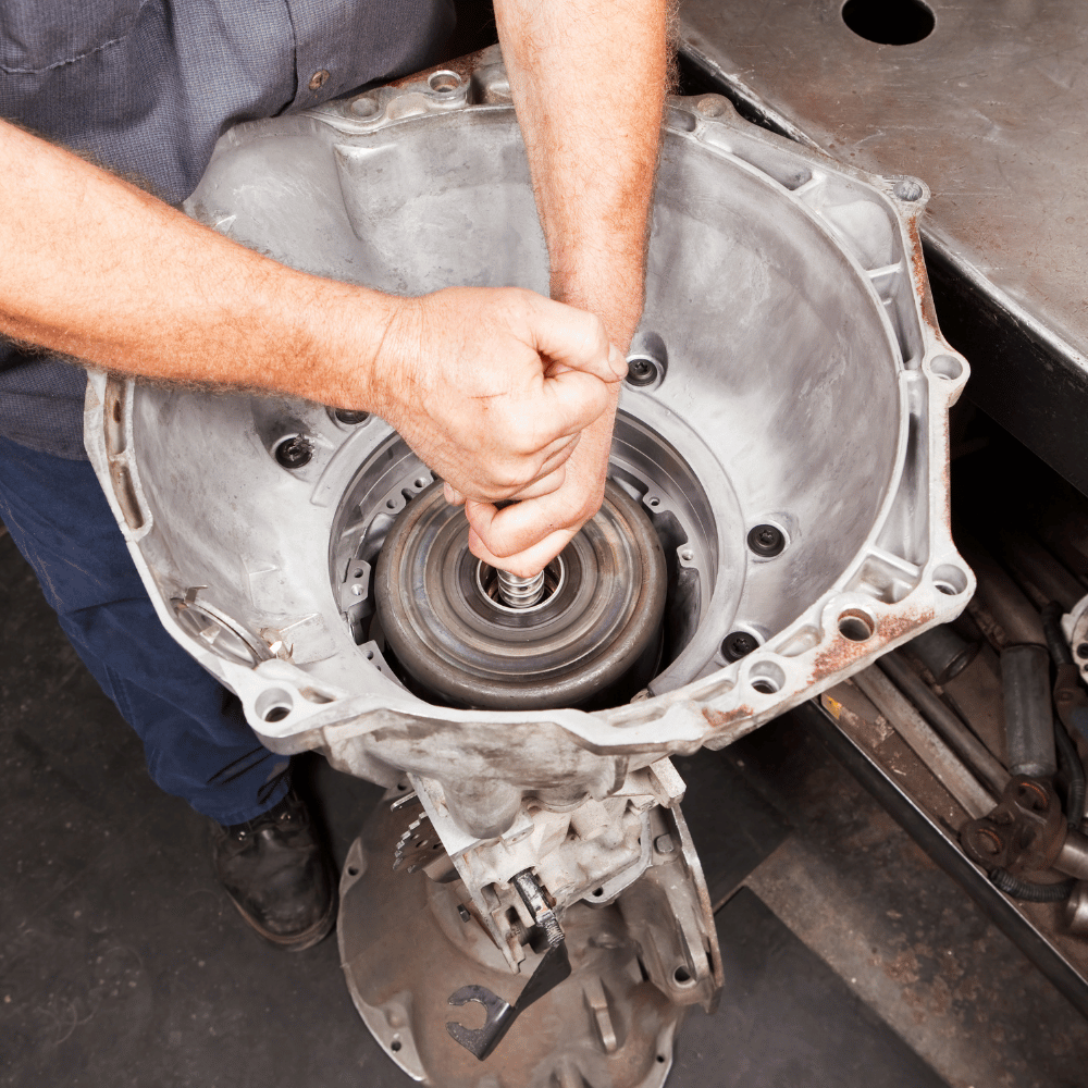 A man is working on a gearbox in a garage
