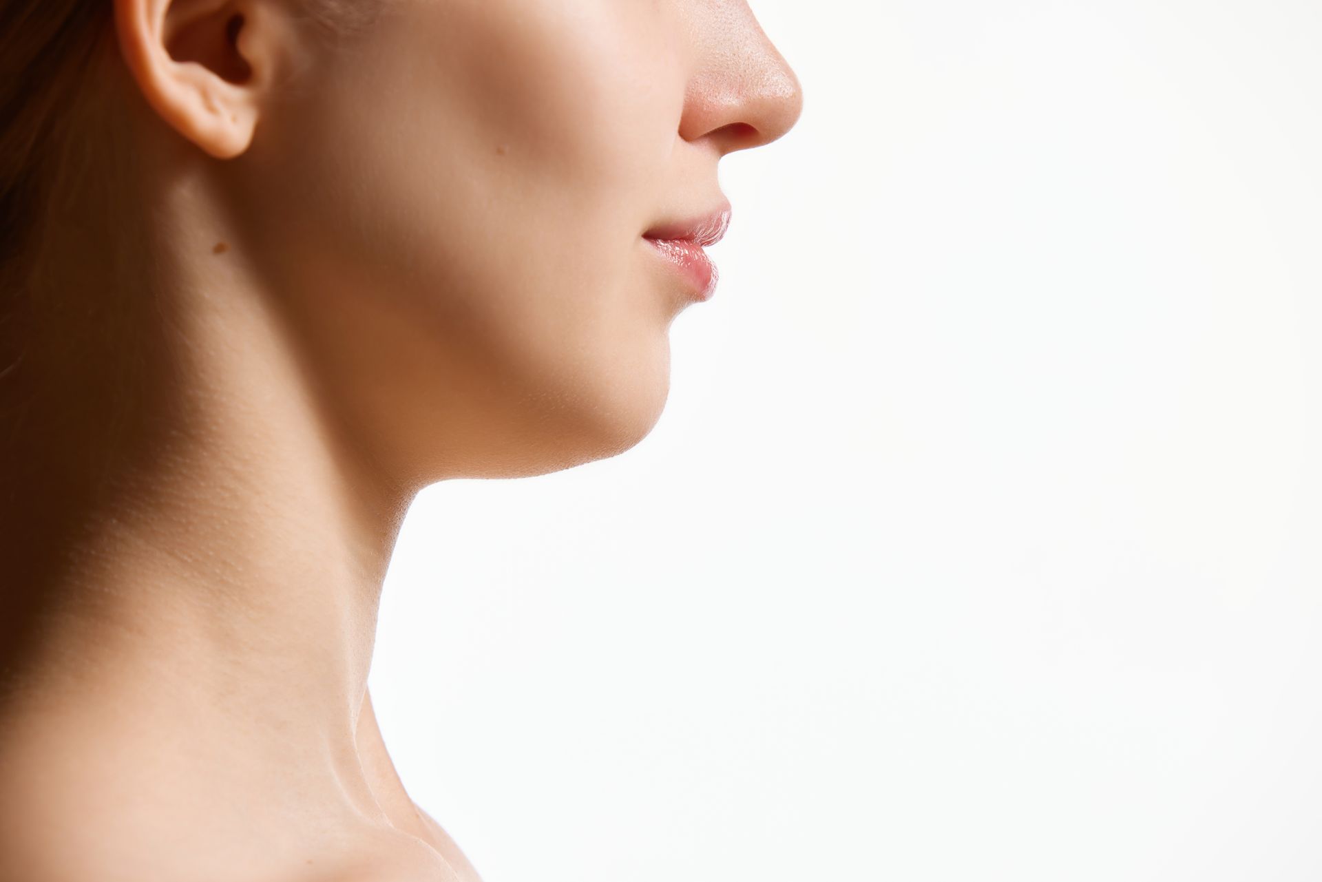 Profile view of a person with fair skin, lips slightly parted, and visible neck, against a white background.