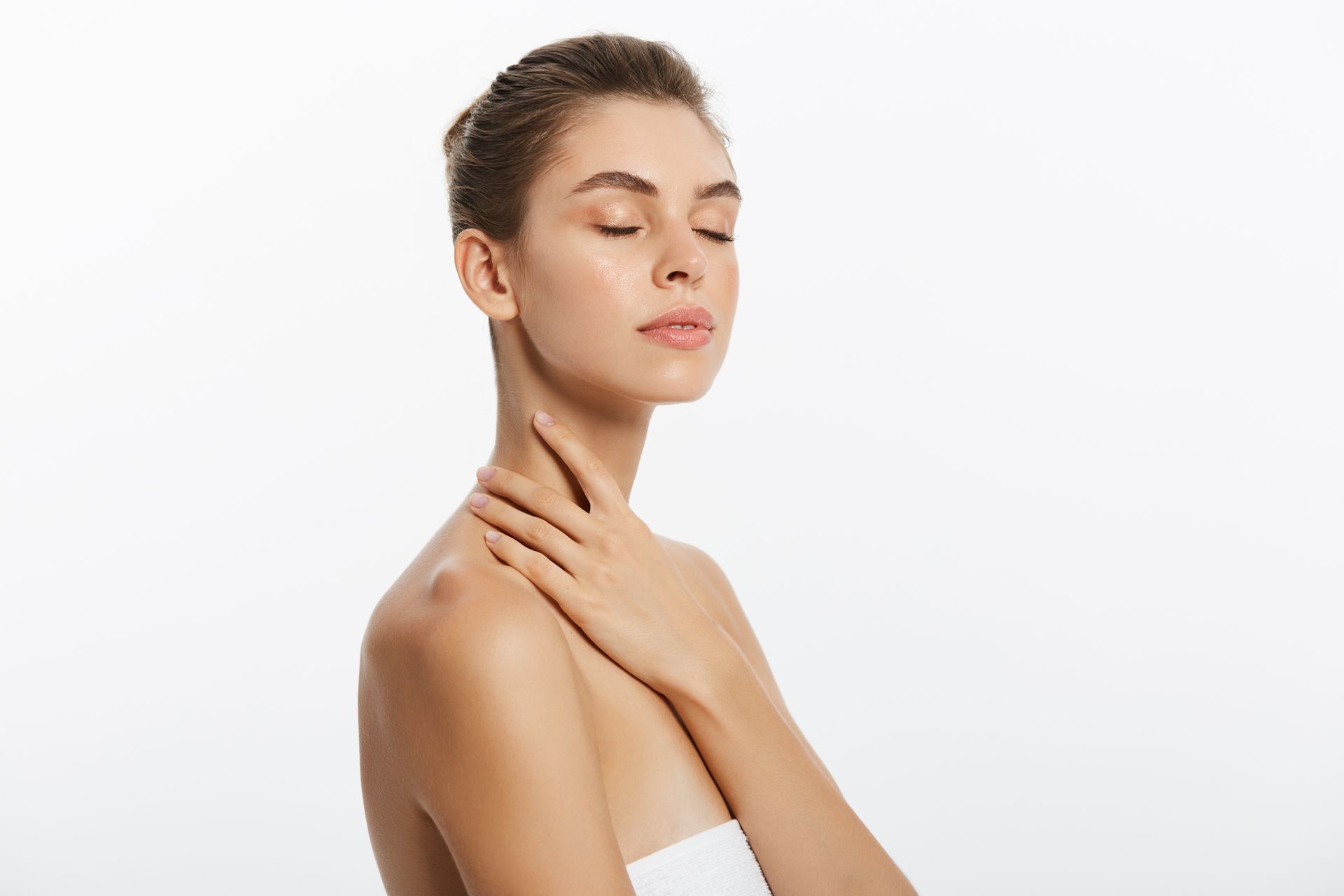 A woman with her eyes closed is touching her neck and shoulder.