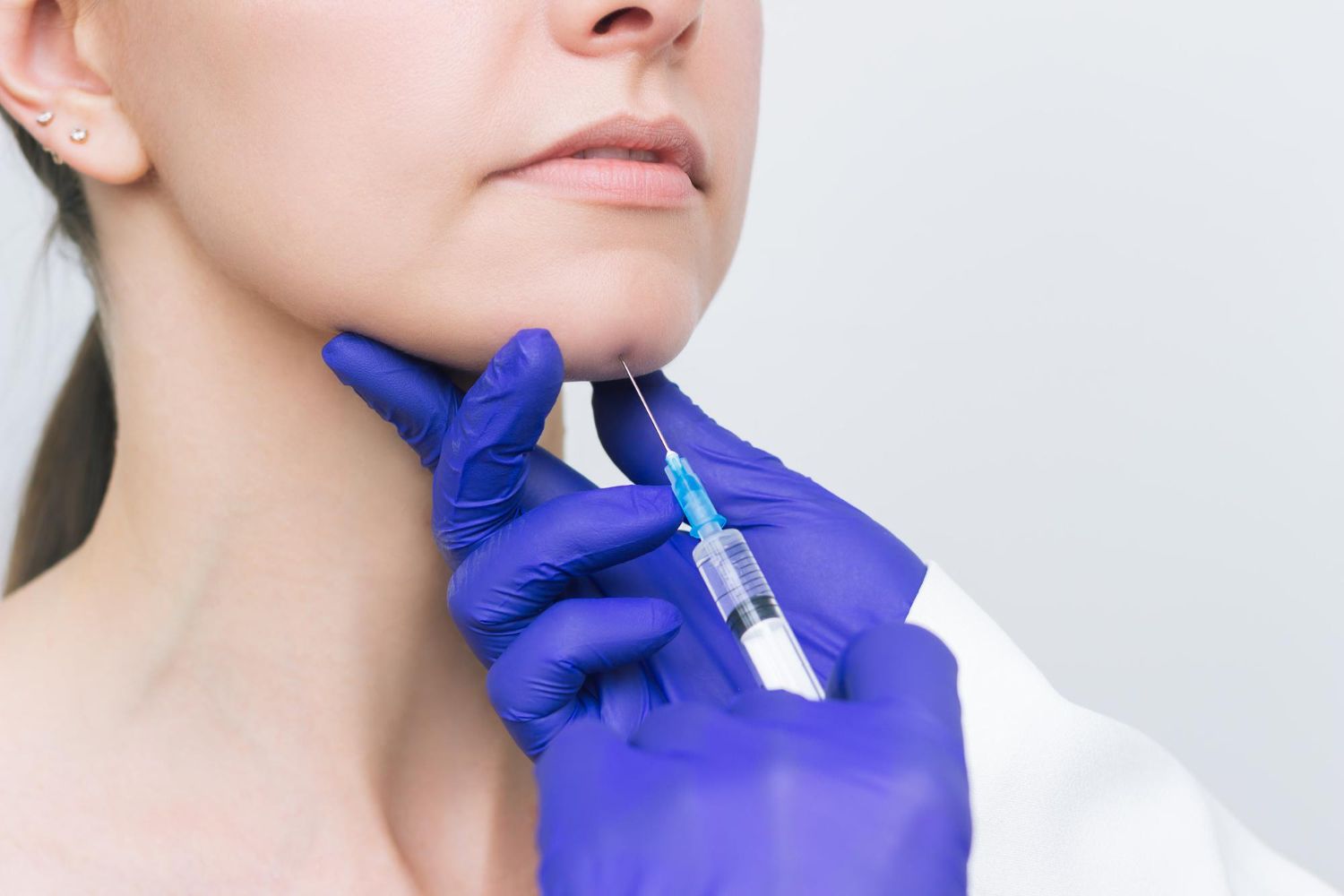 A woman is getting a botox injection in her chin.