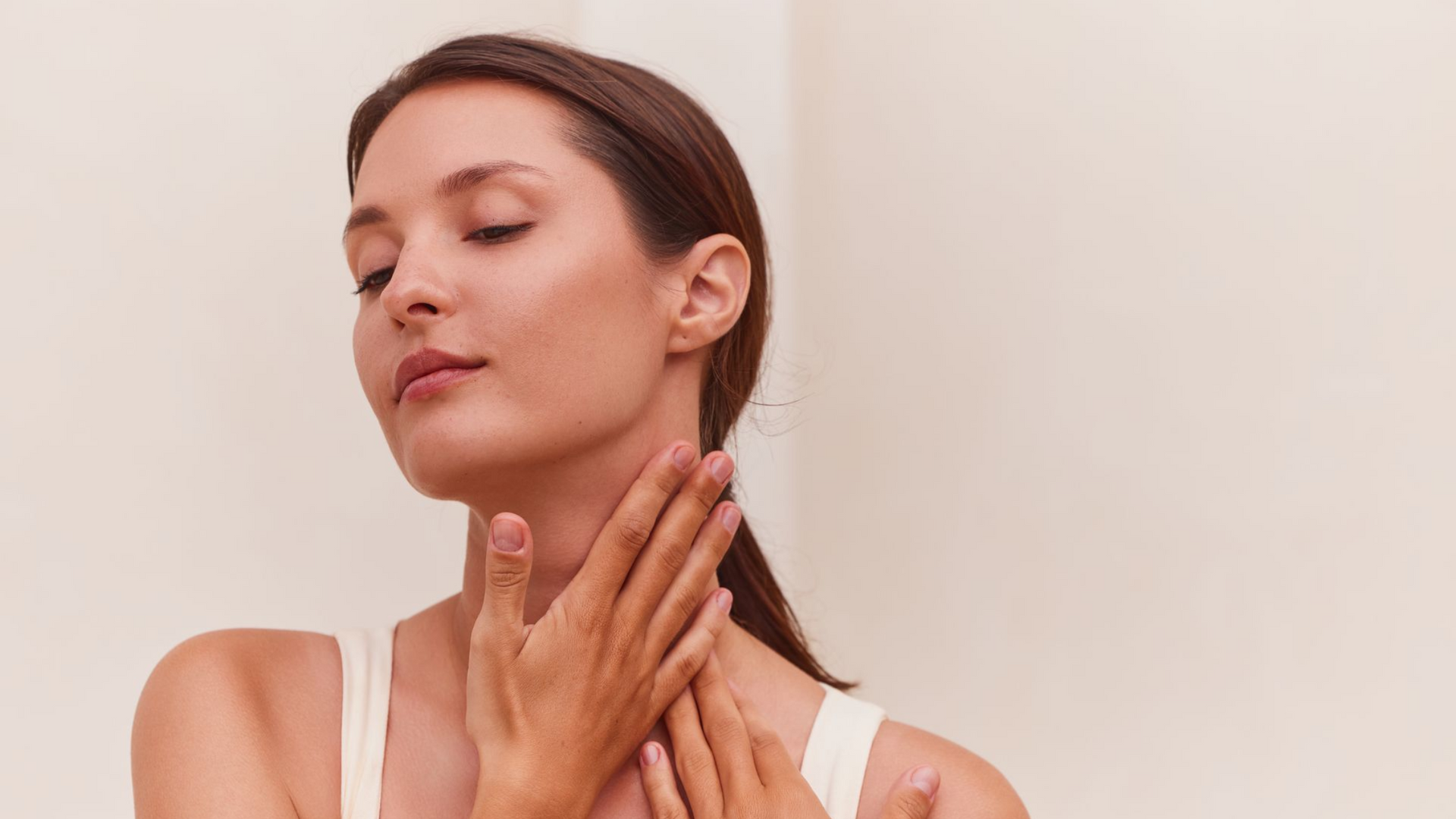 A woman is smiling and touching her face with her hands.