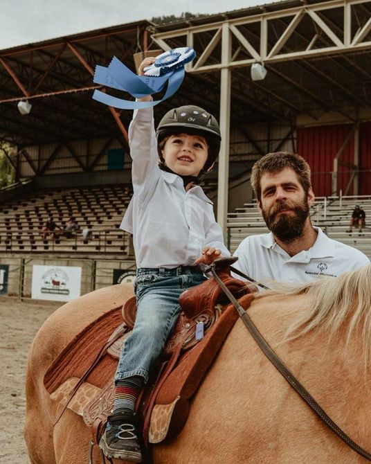 Two men wearing face masks are cooking food in a kitchen.