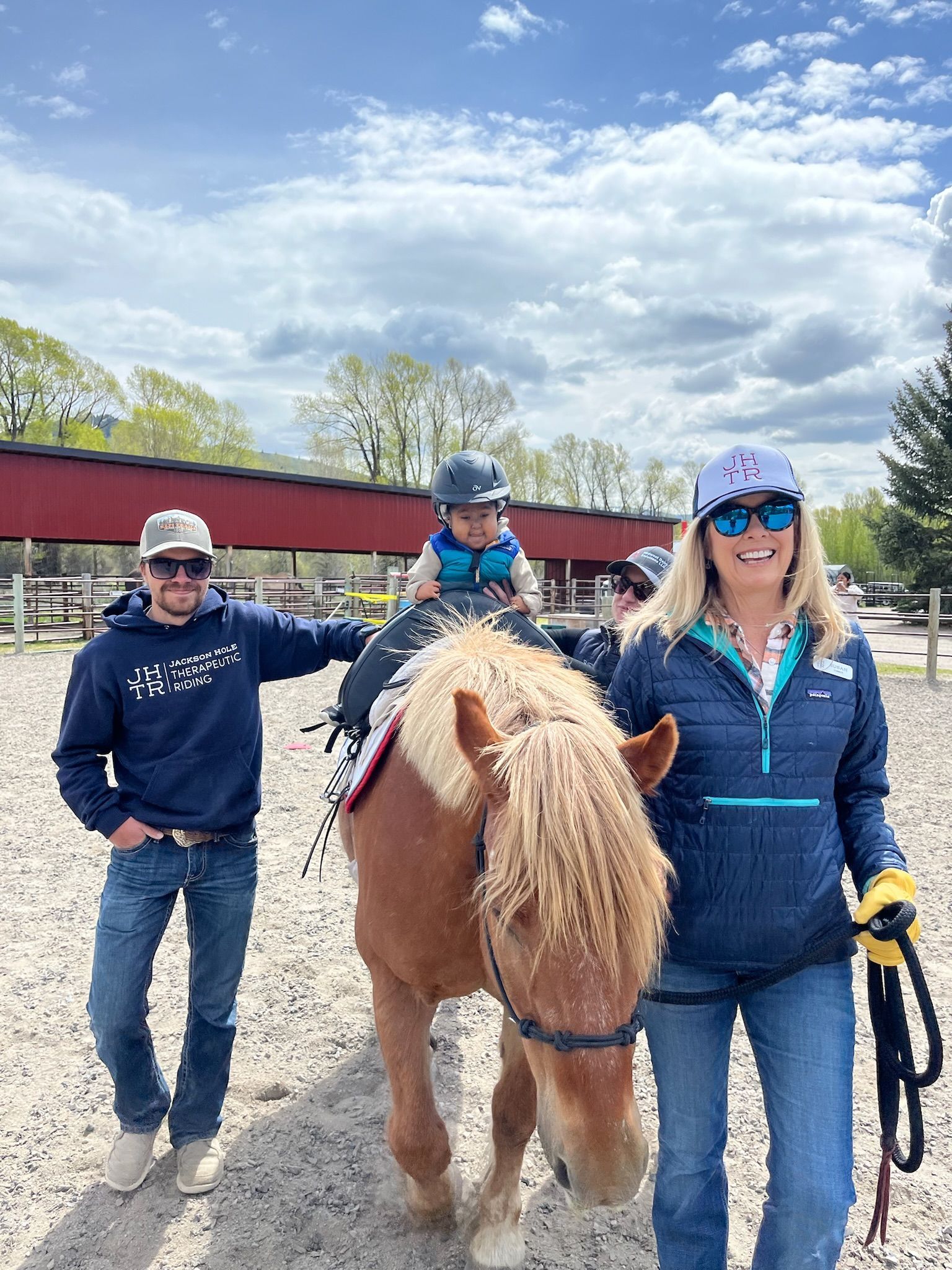 Boy in wheelchair with trophy, horse, and woman outdoors, celebrating success.