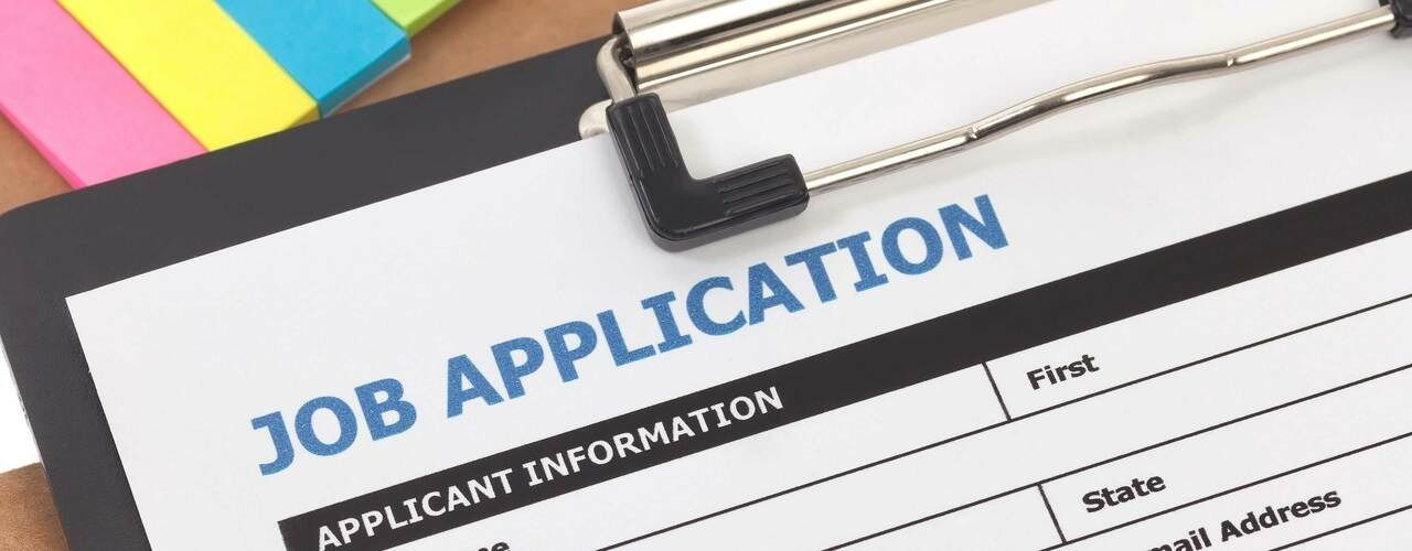 Job application form on a clipboard, with post-it notes in the background.