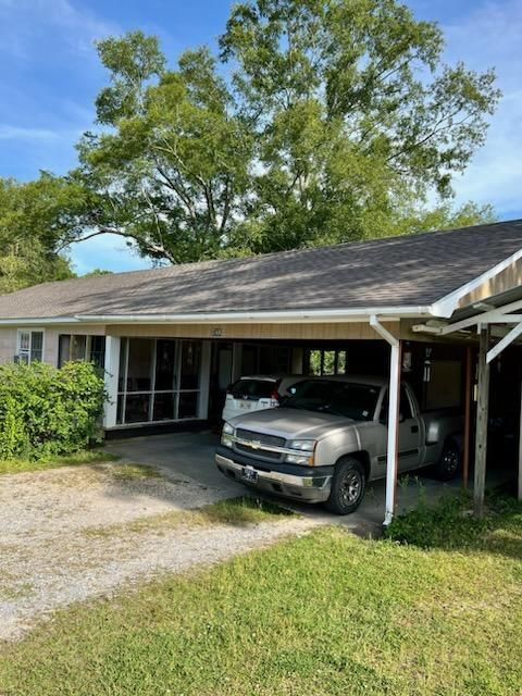 A truck is parked under a canopy in front of a house.