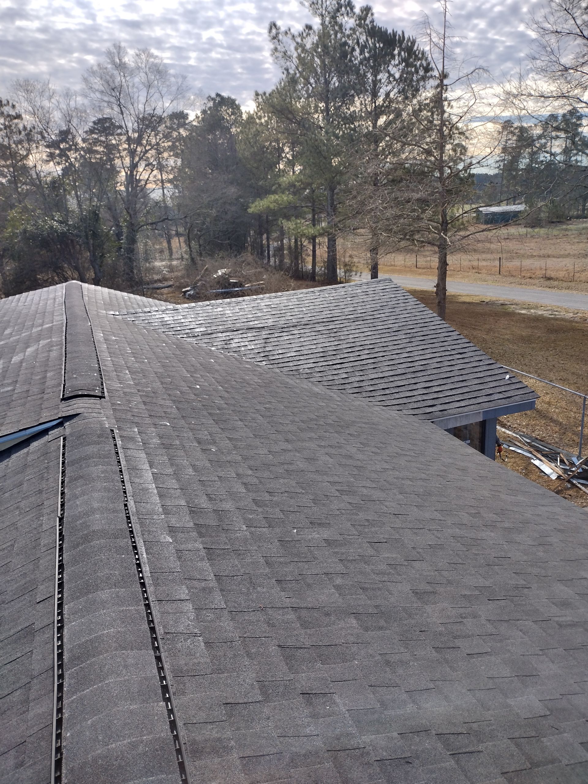 A roof with a lot of shingles on it and trees in the background.