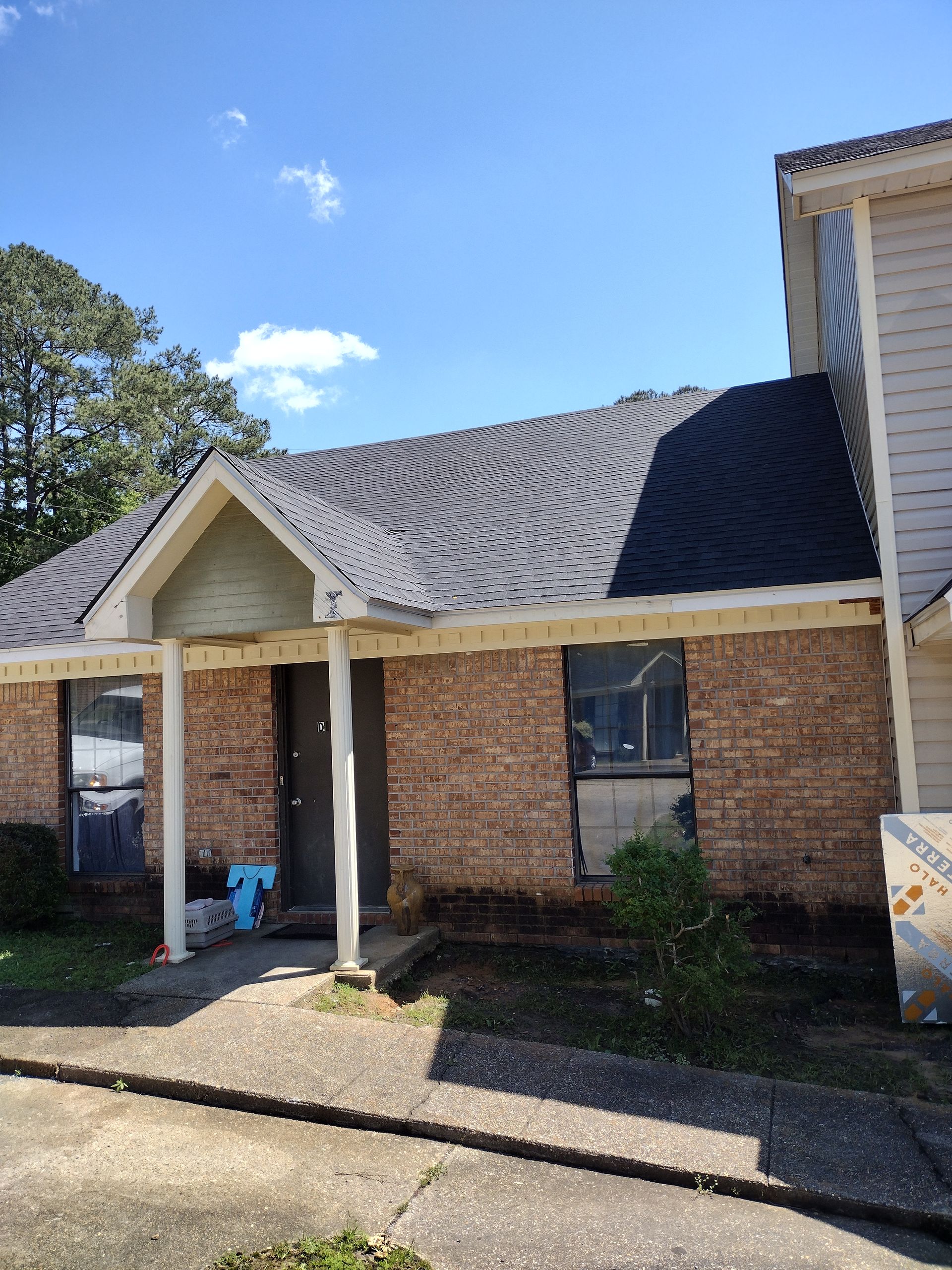 A brick house with a gray roof and a porch