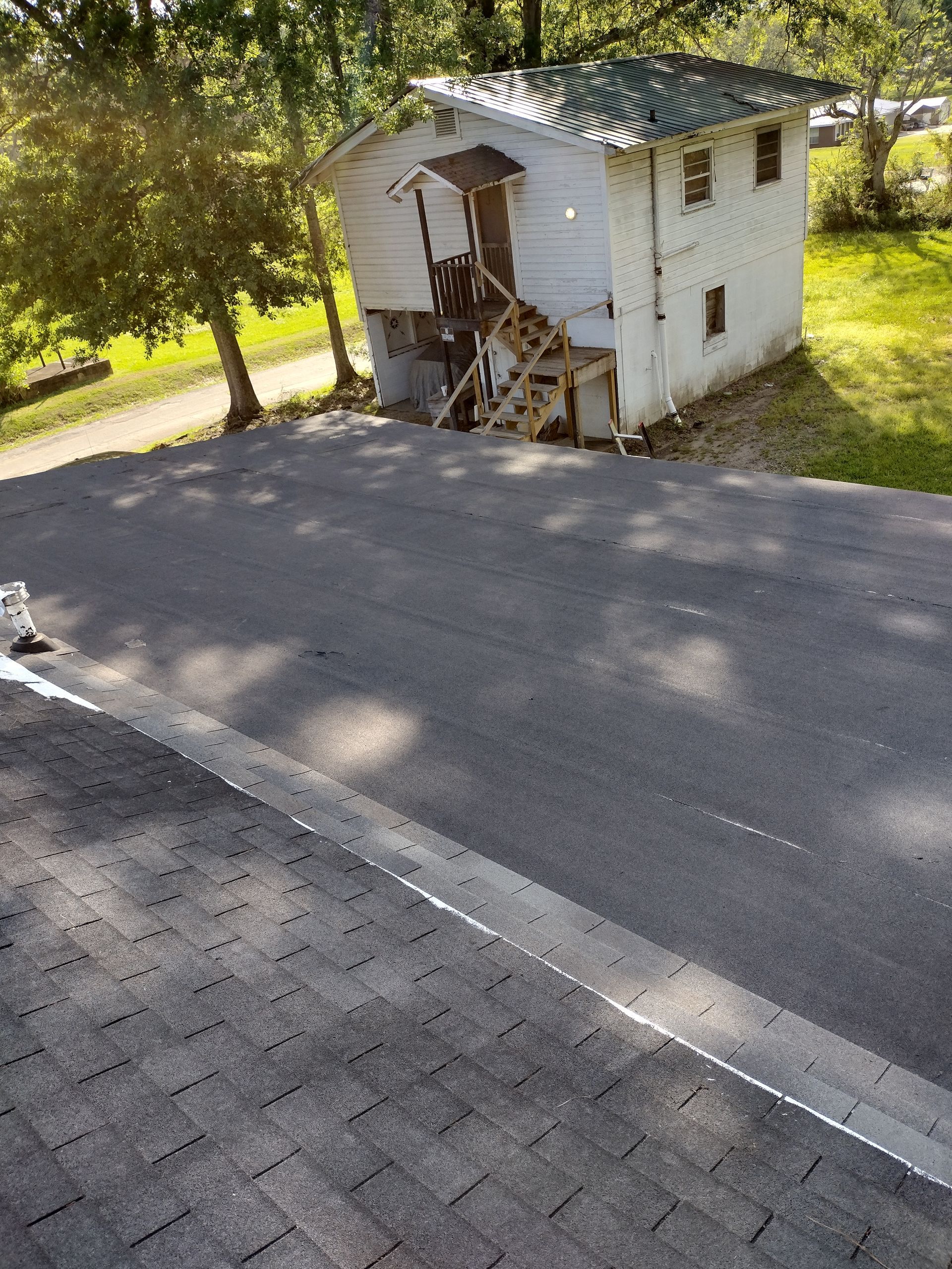 A small white house is sitting on the side of a road.