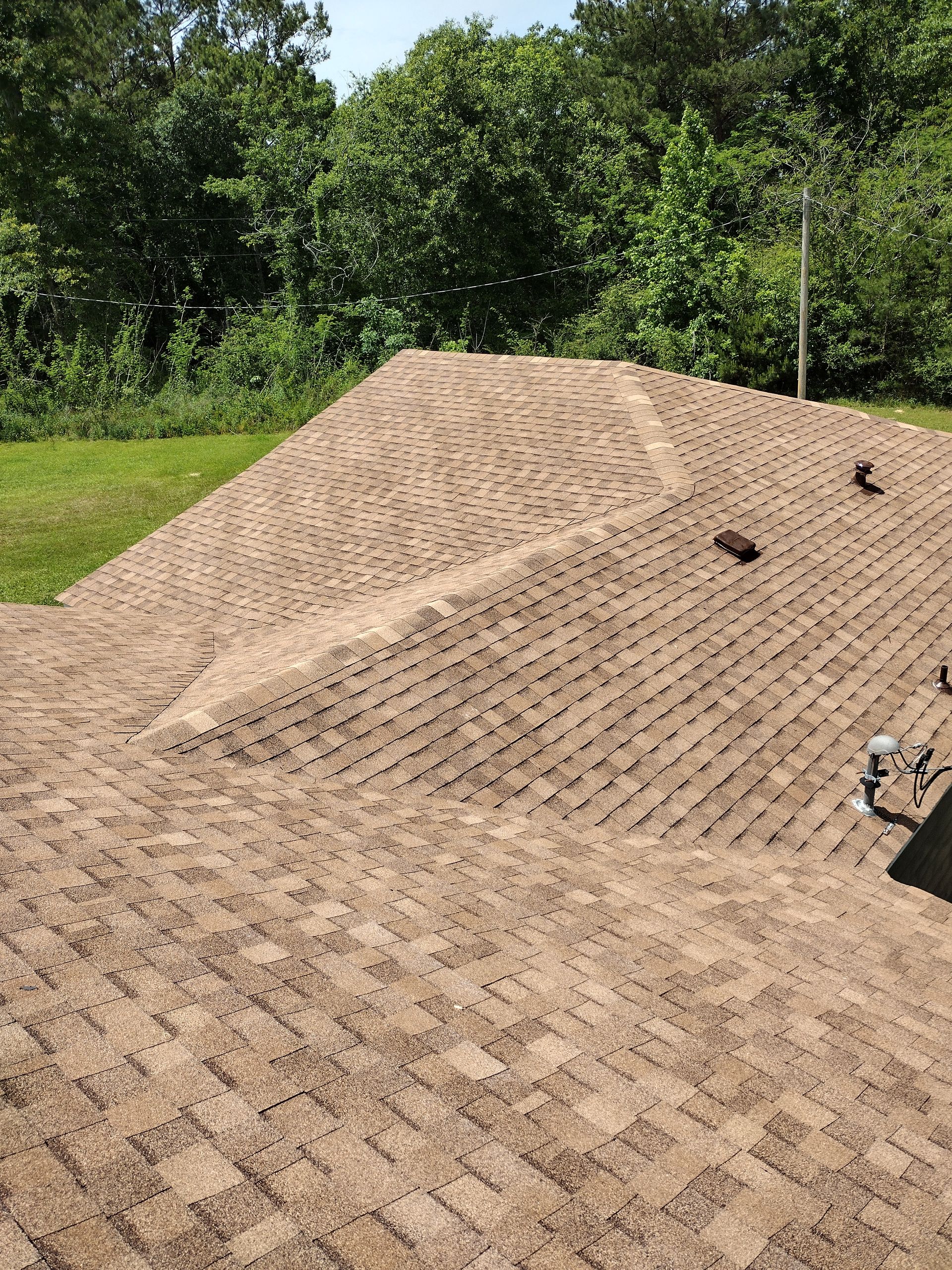 A roof with a lot of shingles on it and trees in the background.