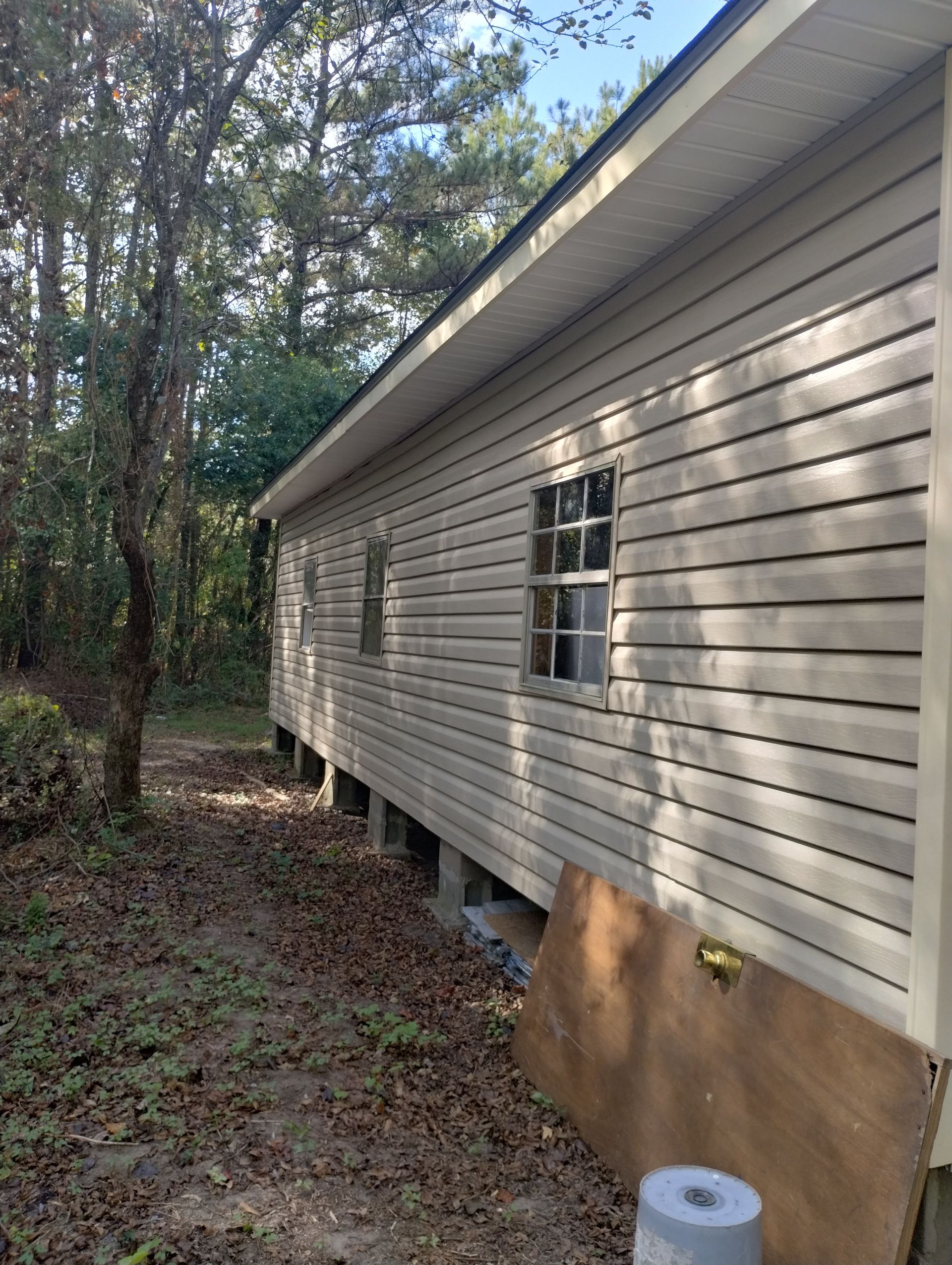A house with a lot of windows is sitting in the middle of a forest.