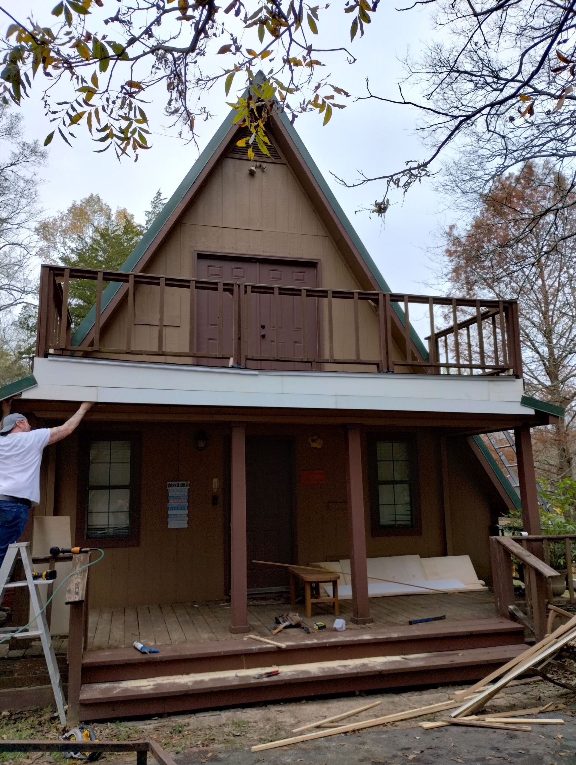 A man is standing on a ladder in front of a house.