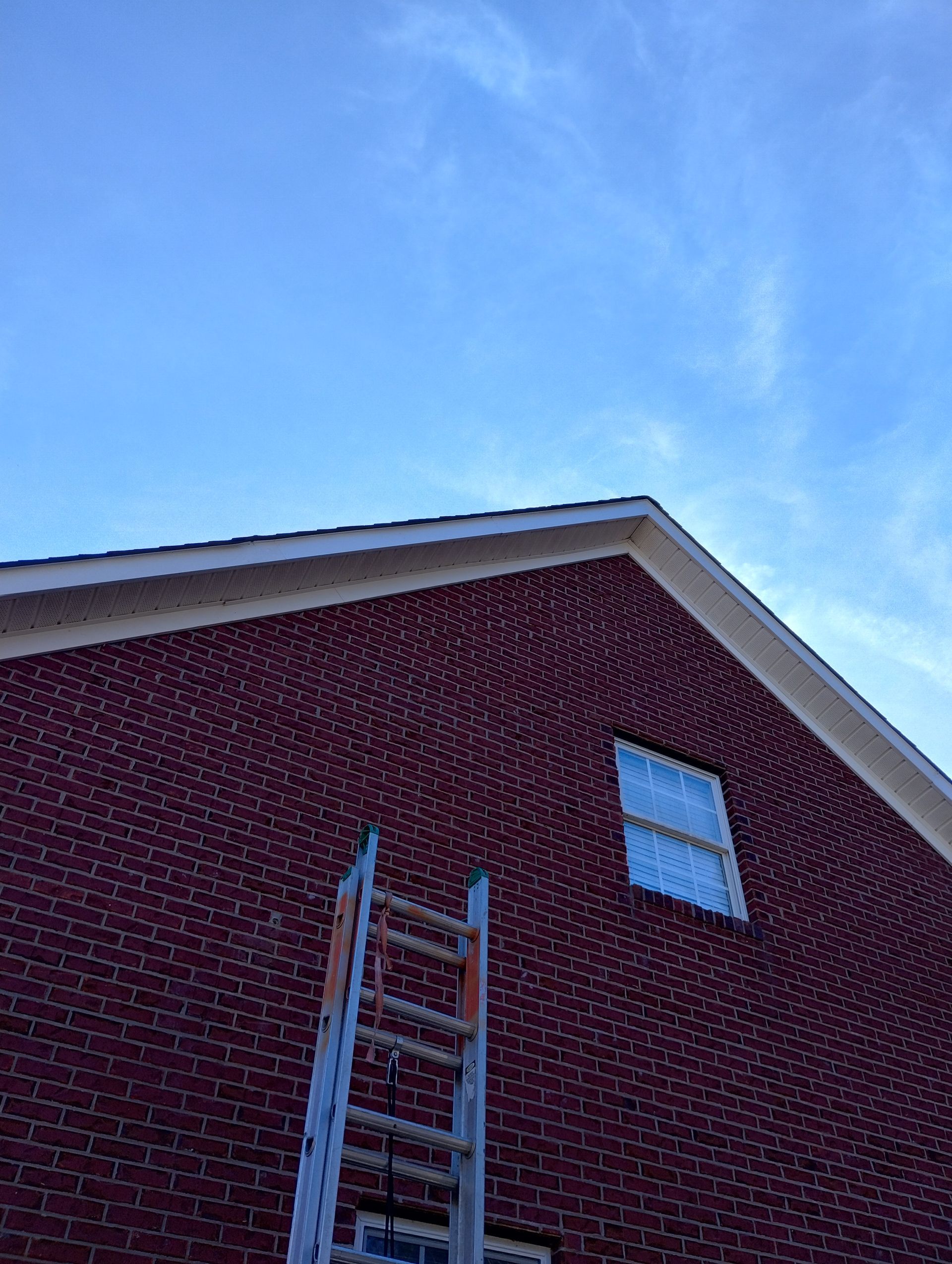A ladder is sitting on the side of a brick building.