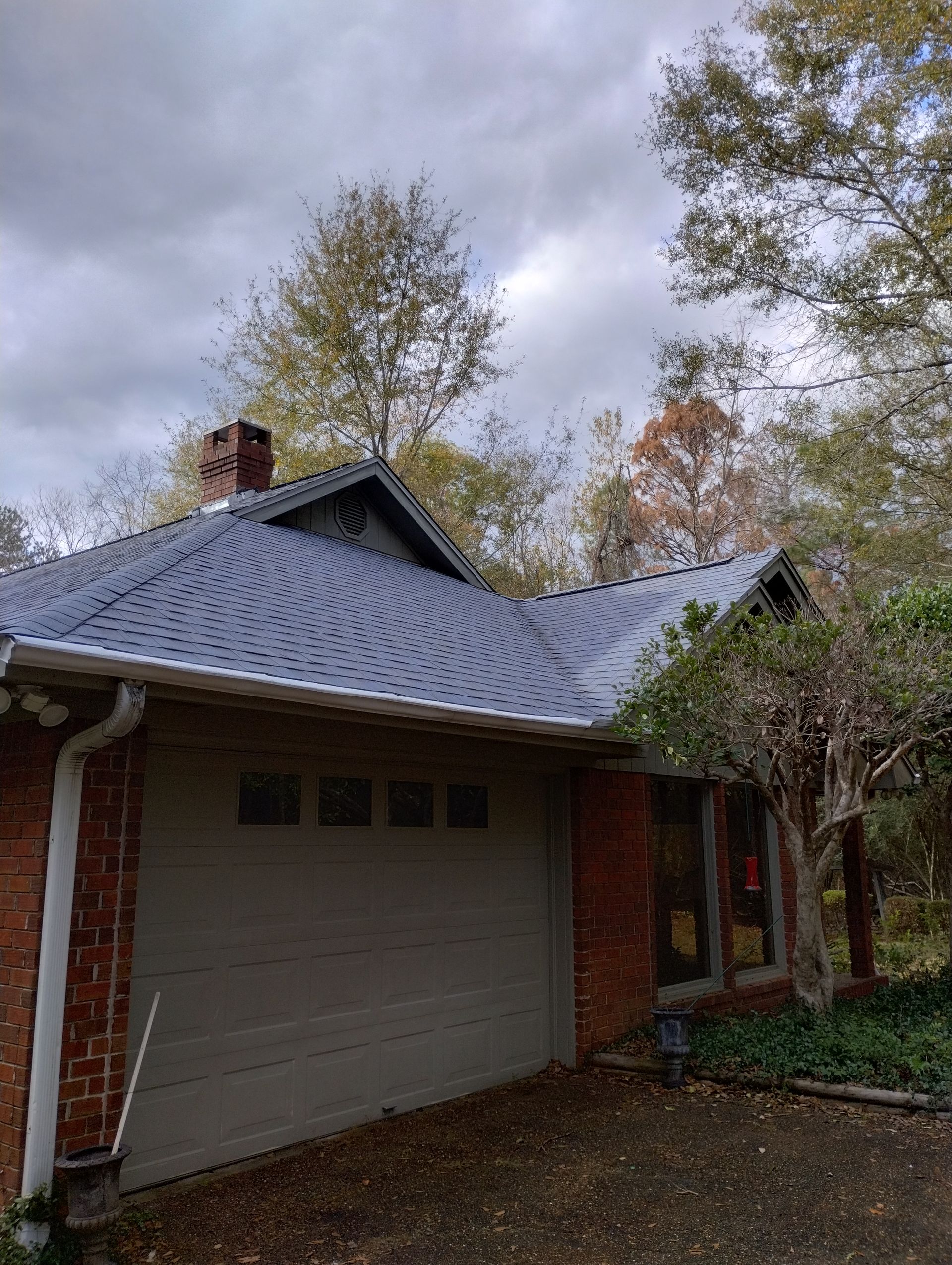 A brick house with a blue roof and a garage door.
