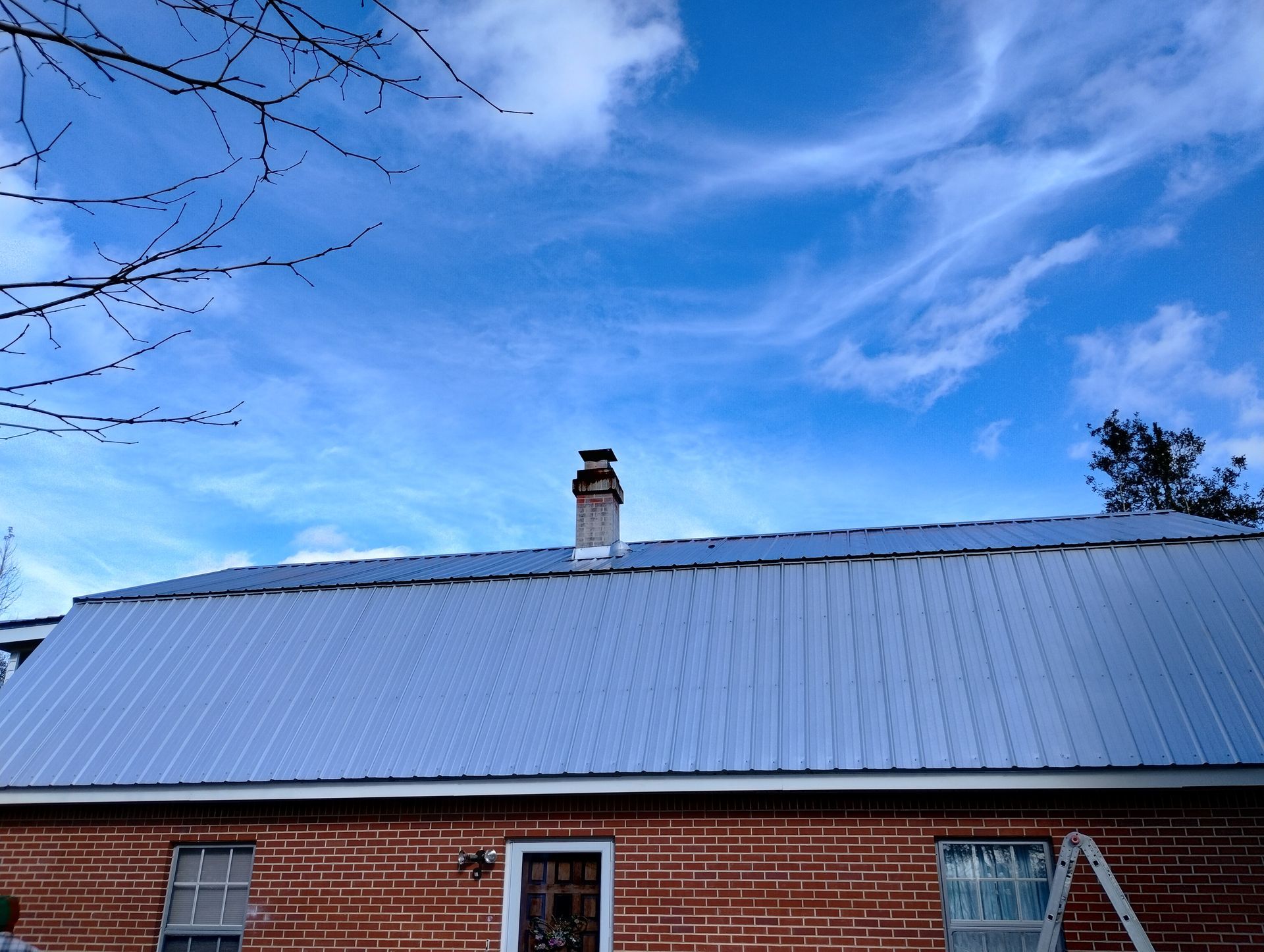 A brick house with a metal roof and chimney