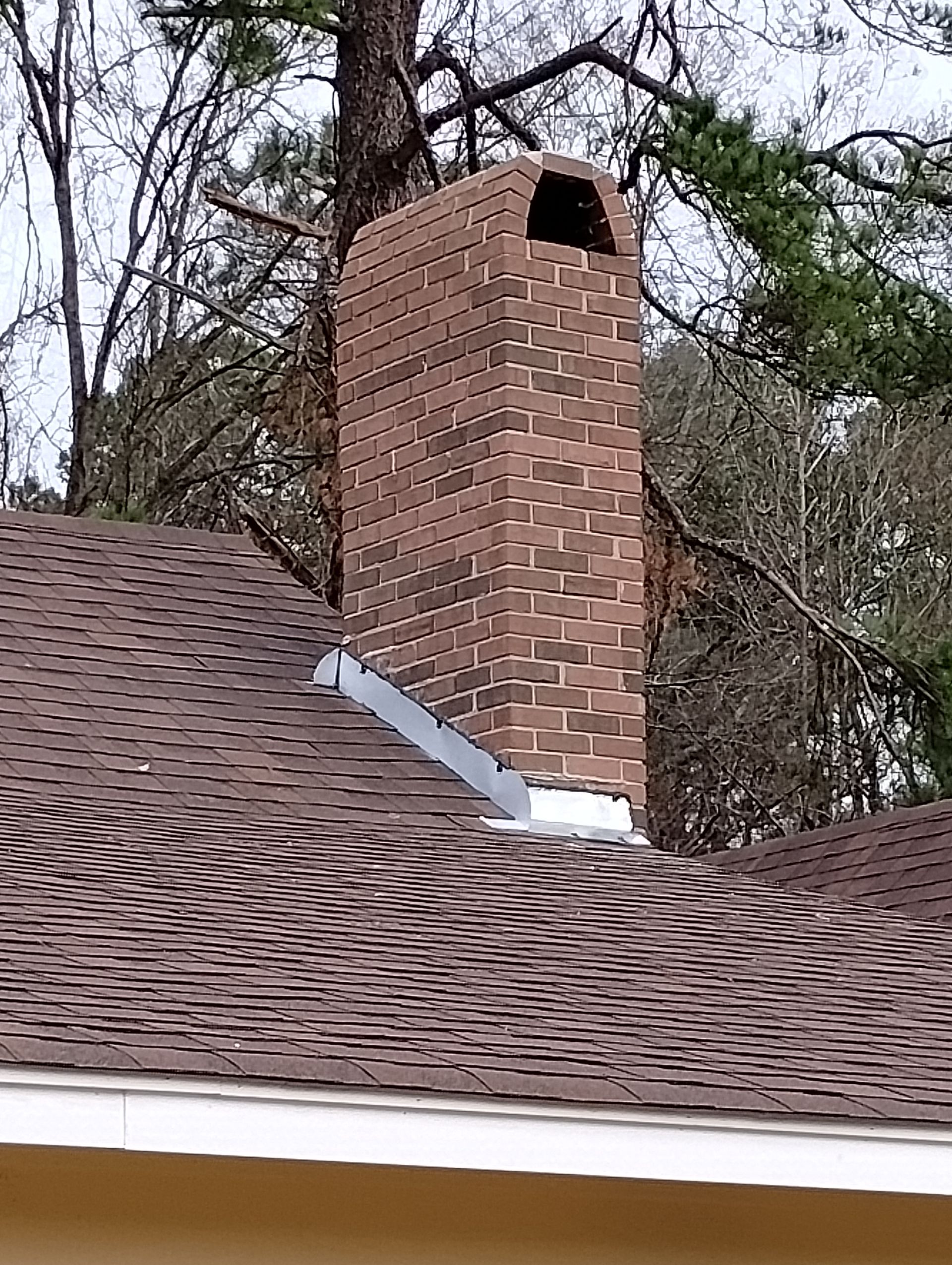 A brick chimney is on the roof of a house.