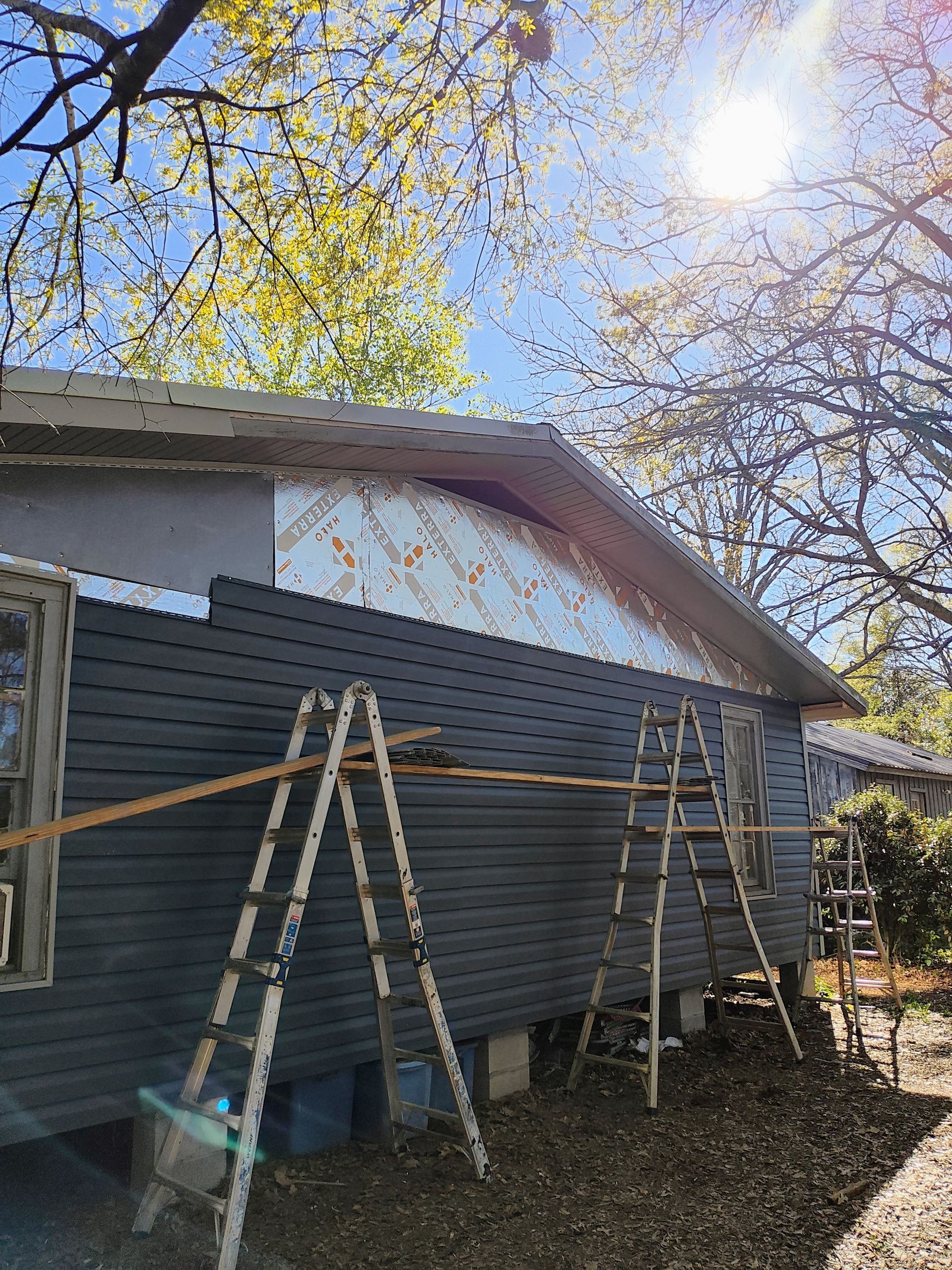 A house is being remodeled with a ladder on the side of it.