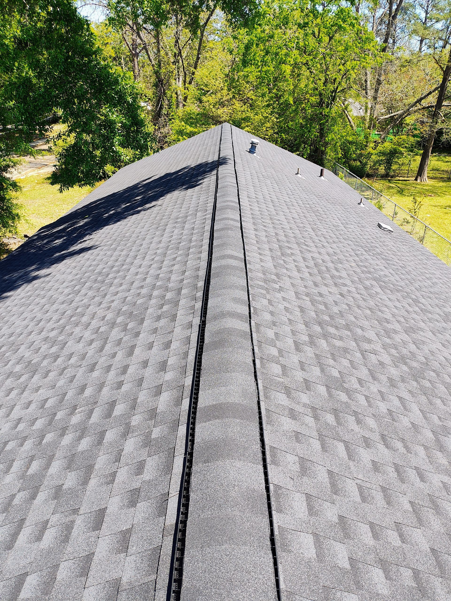 A roof with a lot of shingles and trees in the background.