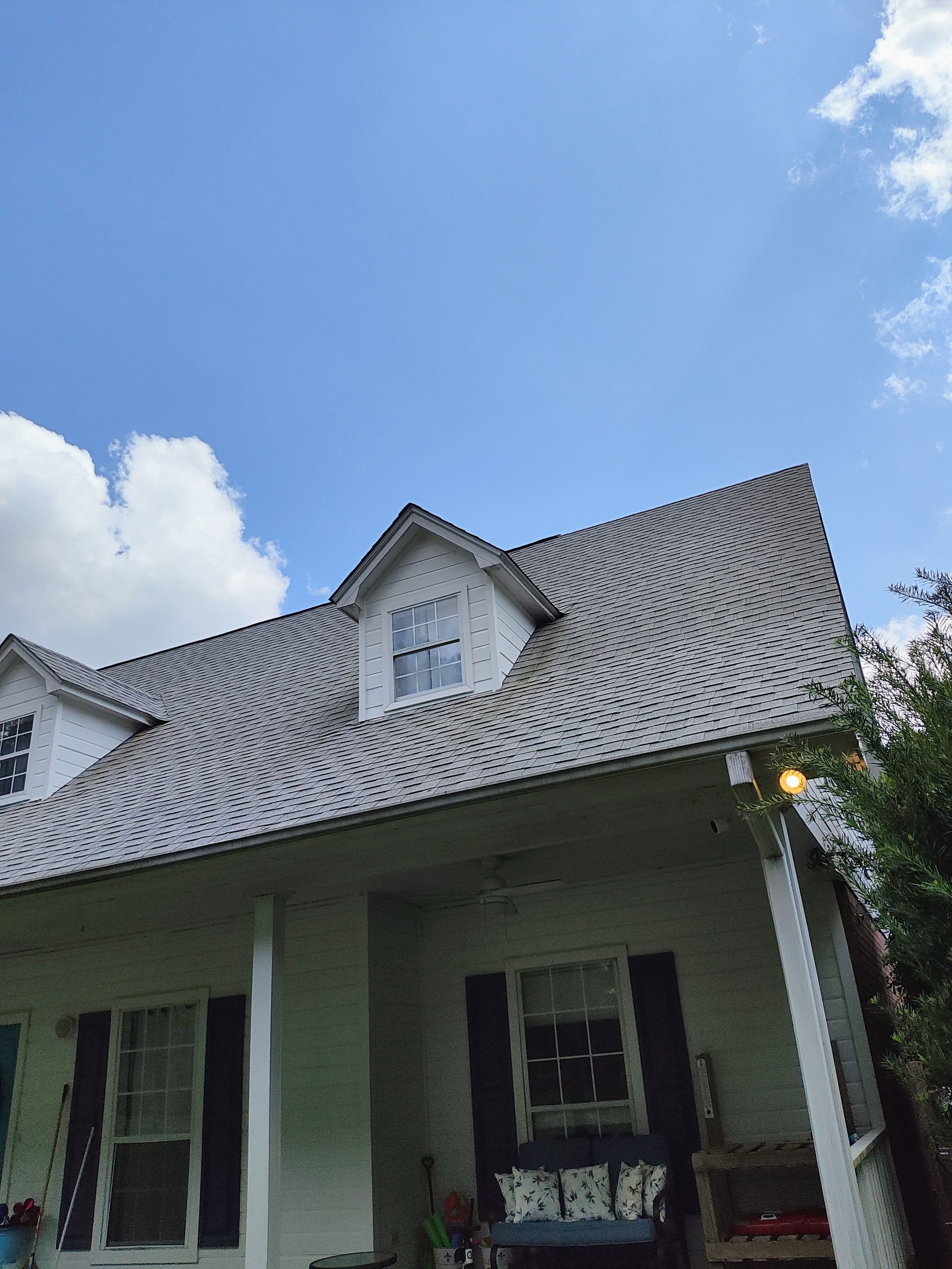 A white house with a gray roof and a blue sky in the background.