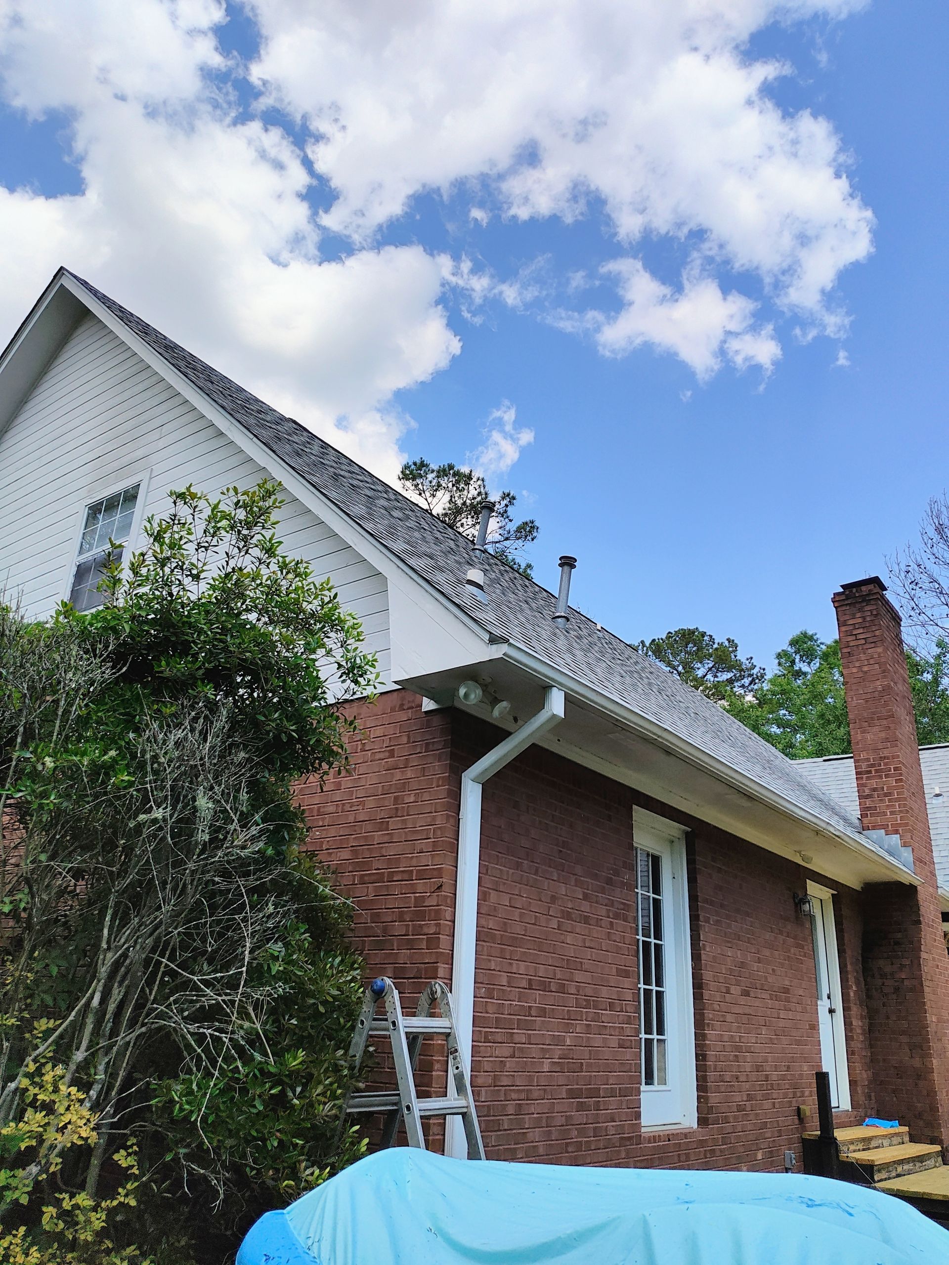 A ladder is sitting in front of a brick house.