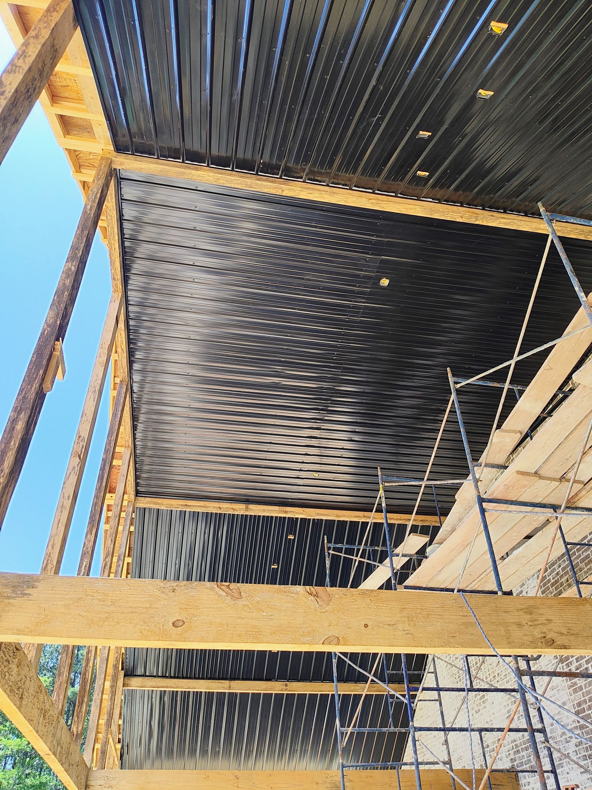 A building under construction with a black roof and scaffolding.
