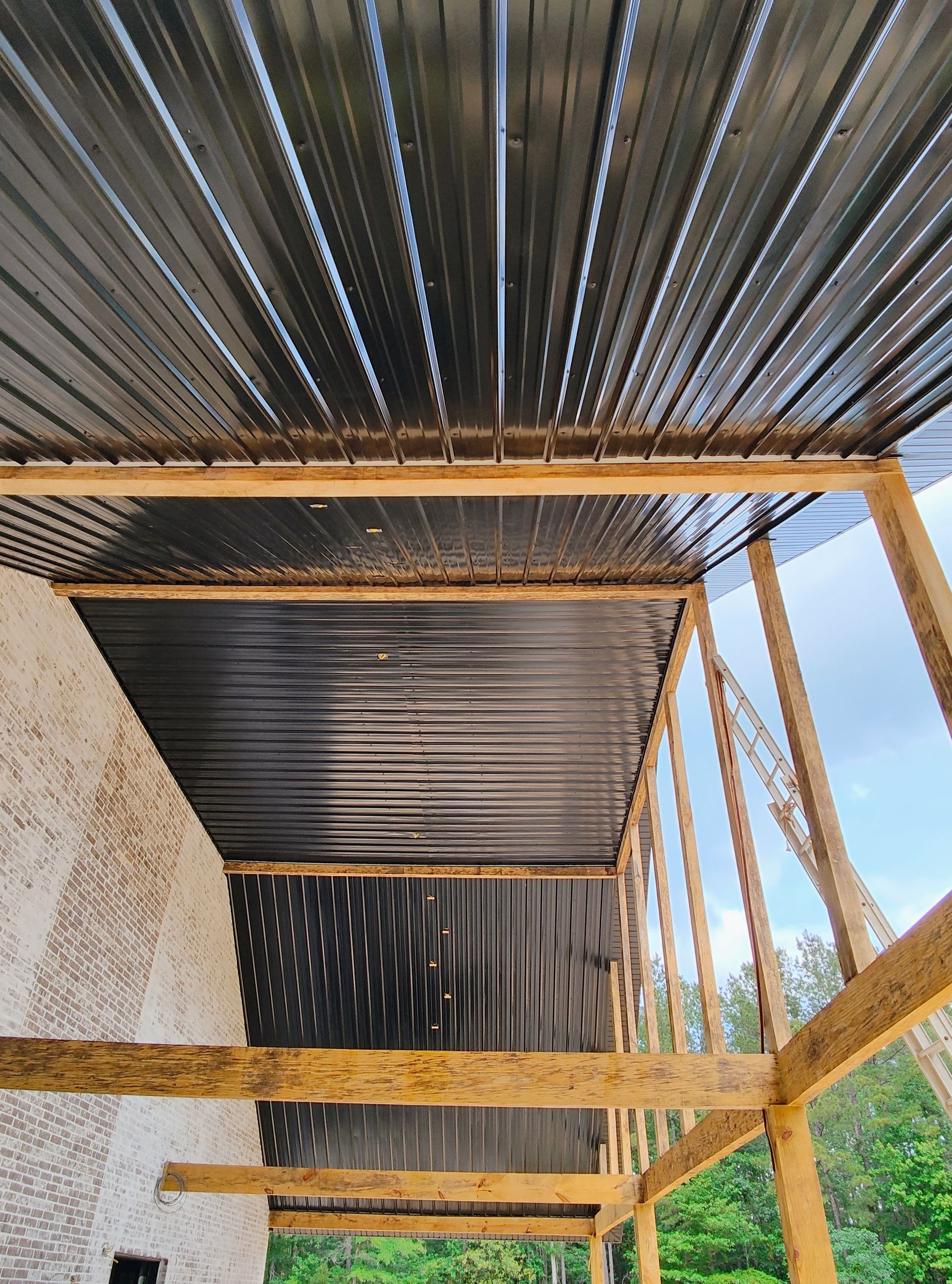 The ceiling of a building with a metal roof and wooden beams.