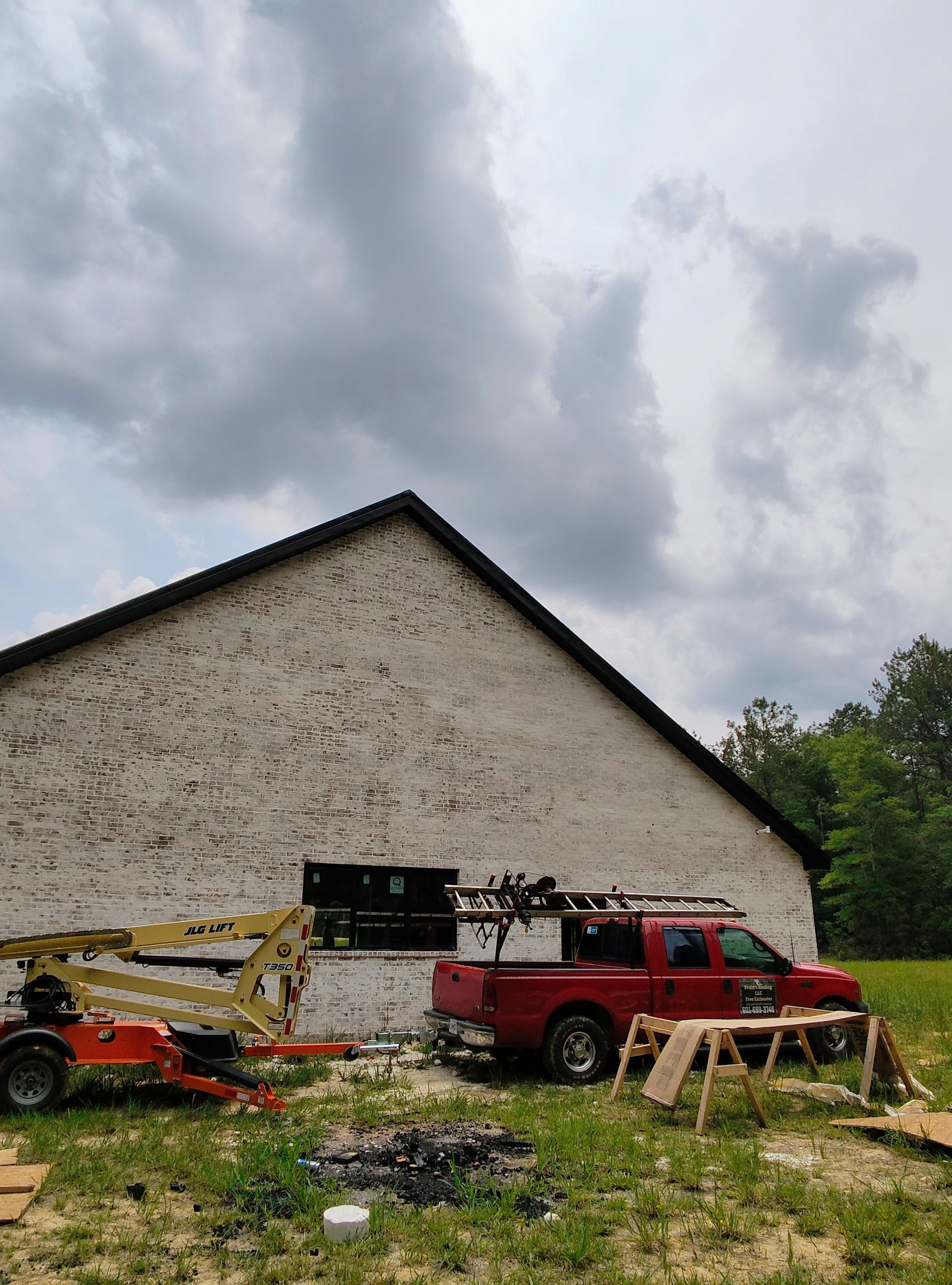 A red truck is parked in front of a large white building.