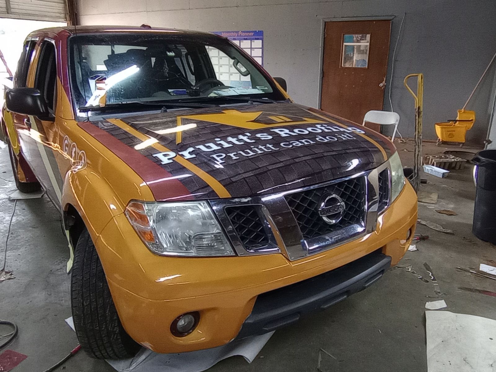 A yellow nissan truck is sitting in a garage.