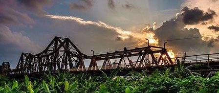 A bridge over a river with a sunset in the background.