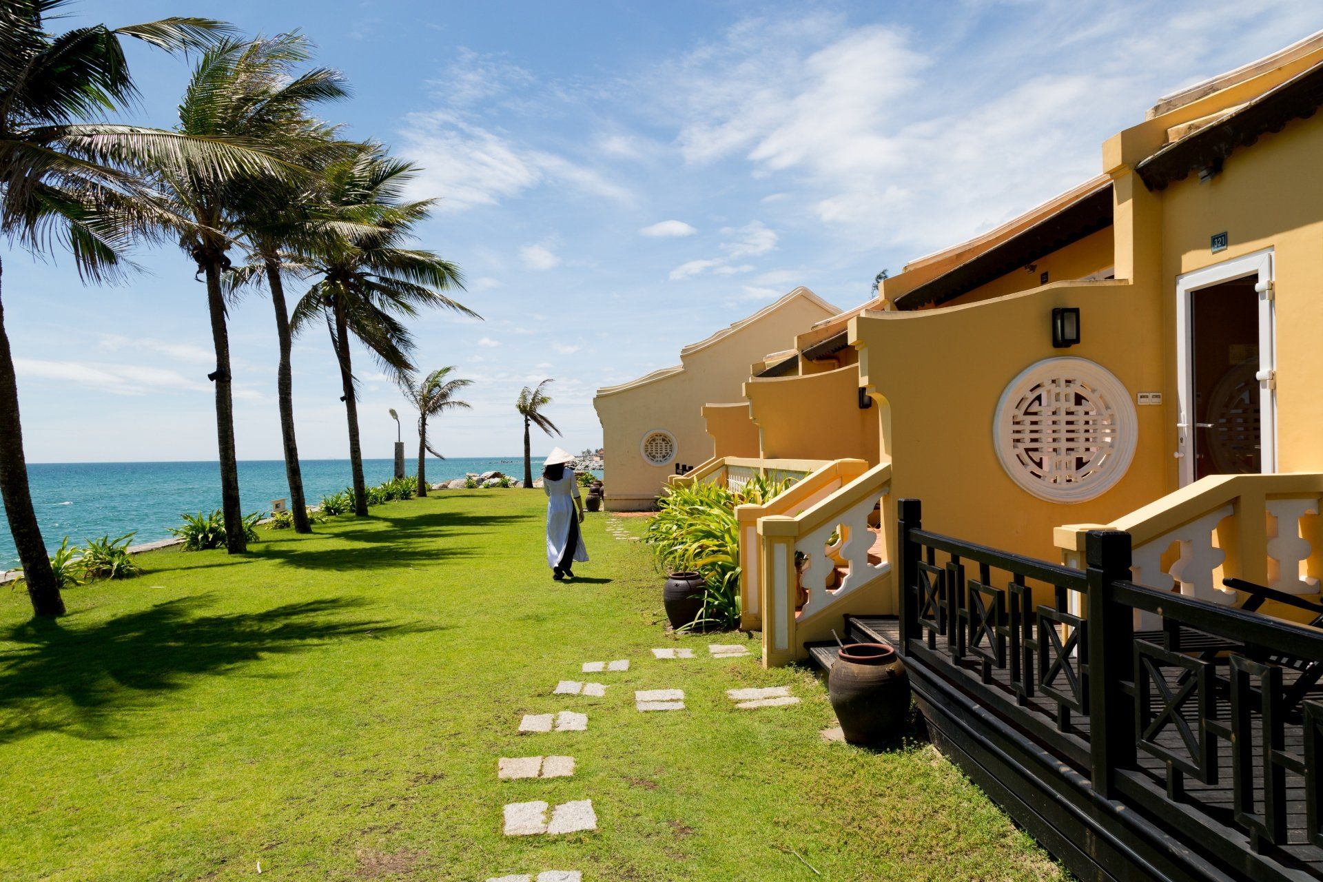 A woman is walking in front of a row of houses near the ocean.