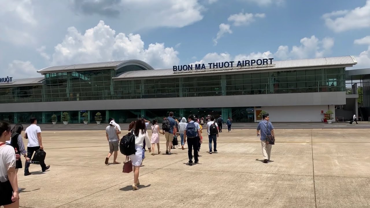 A group of people are walking in front of an airport building.