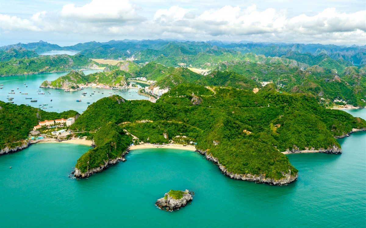 An aerial view of a tropical island surrounded by water and mountains.
