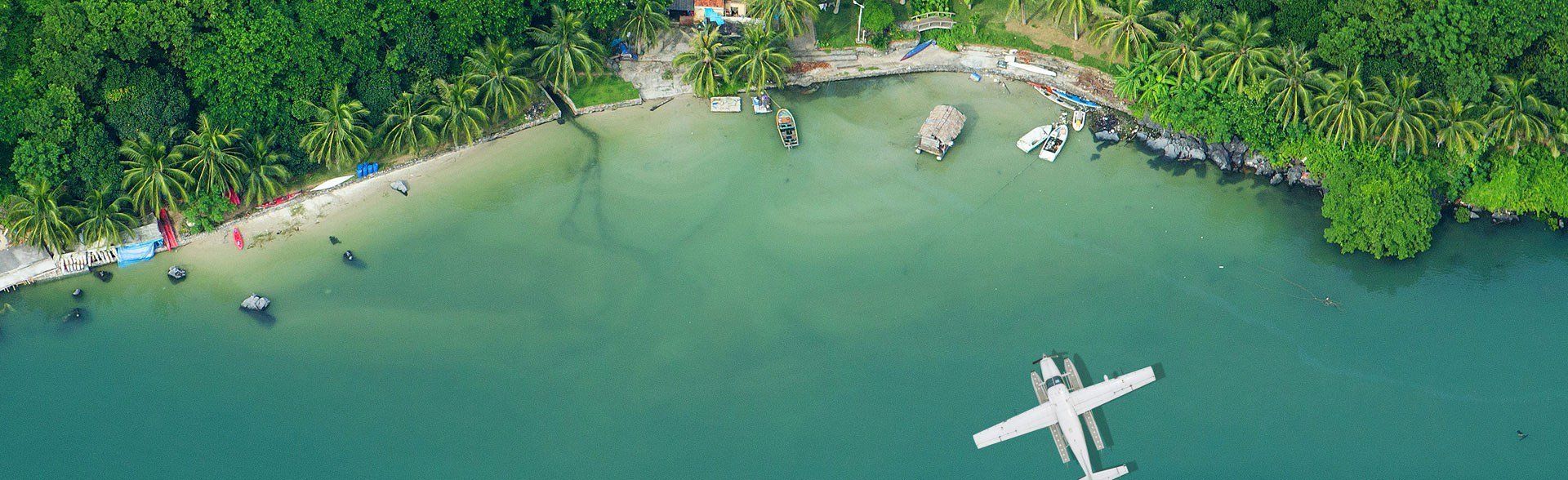 An aerial view of a small plane flying over a body of water.