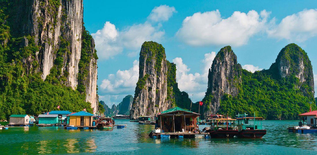 A group of boats are floating on top of a body of water surrounded by mountains.