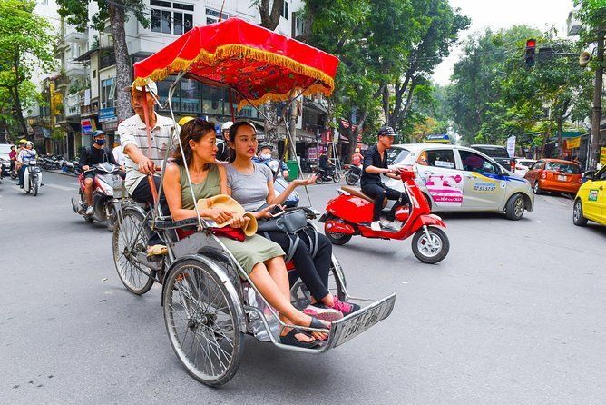 A group of people are riding a rickshaw down a busy street.