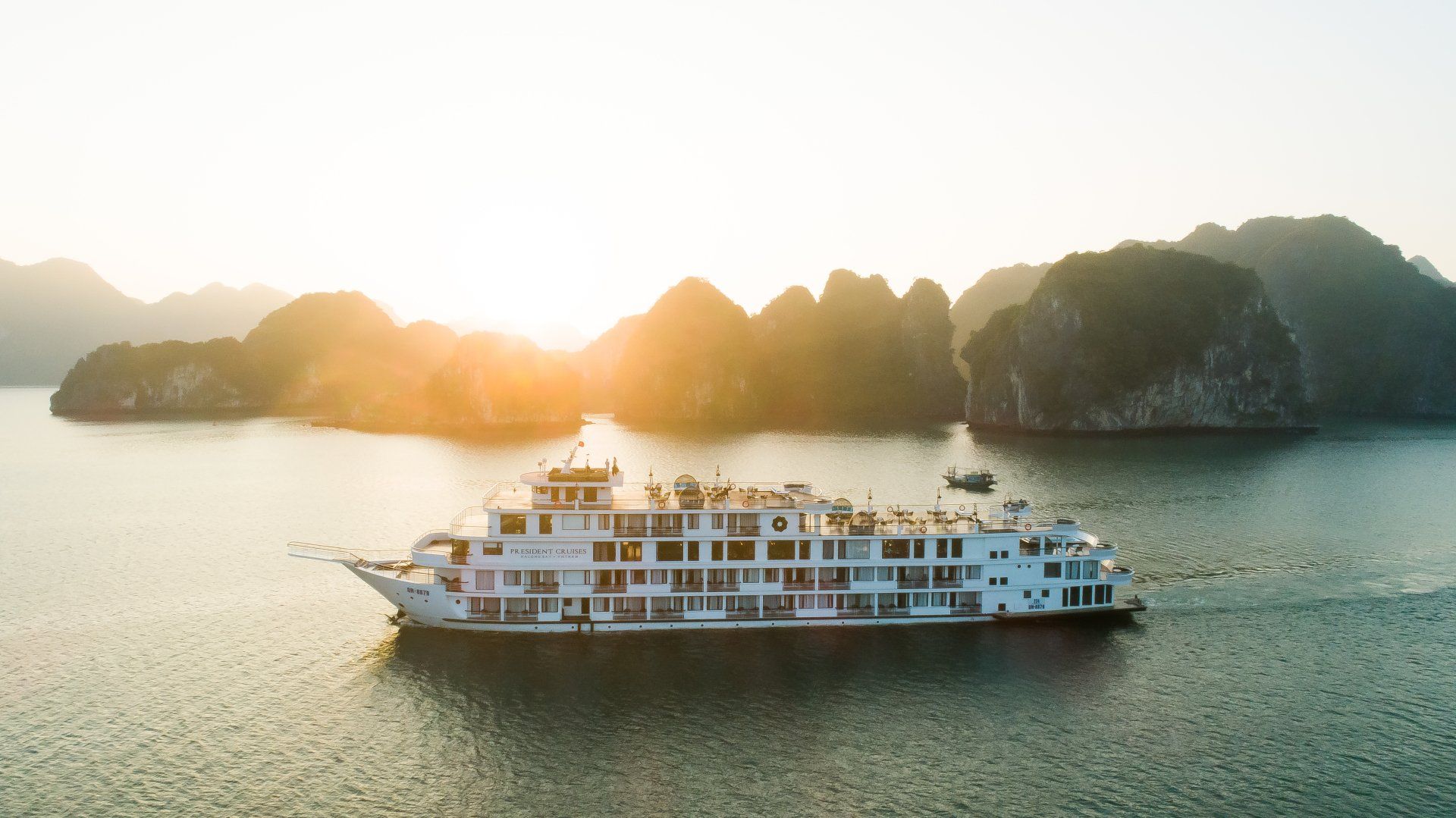 An aerial view of a cruise ship in the ocean at sunset.