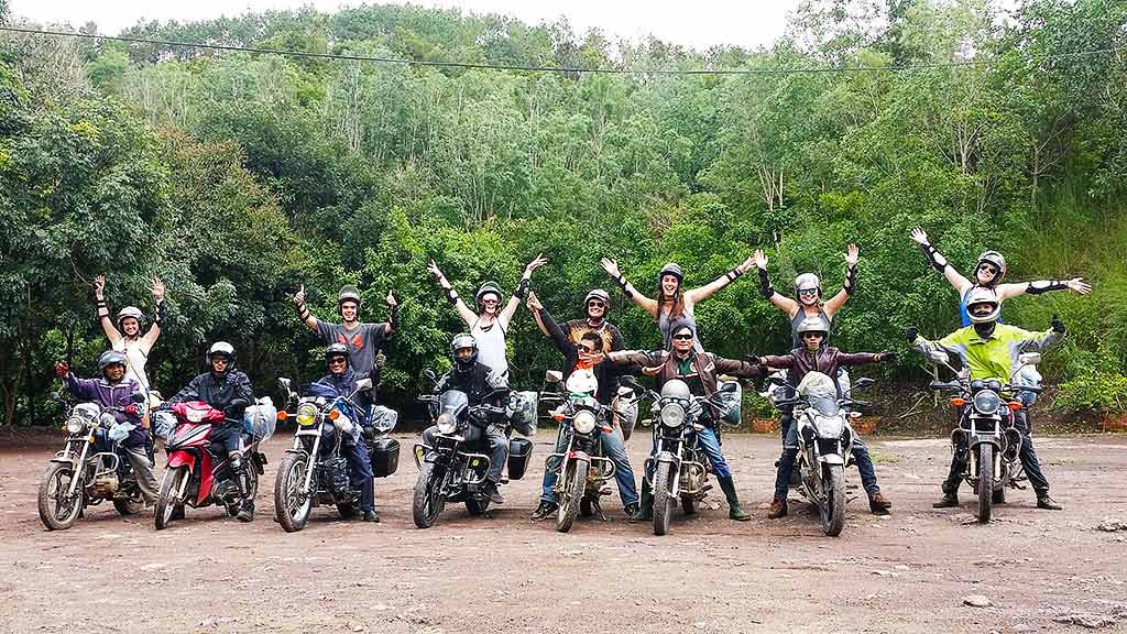 A group of people standing next to each other on motorcycles.
