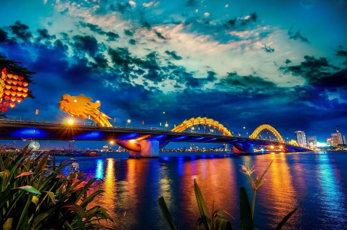A bridge over a body of water at night with a dragon on it.