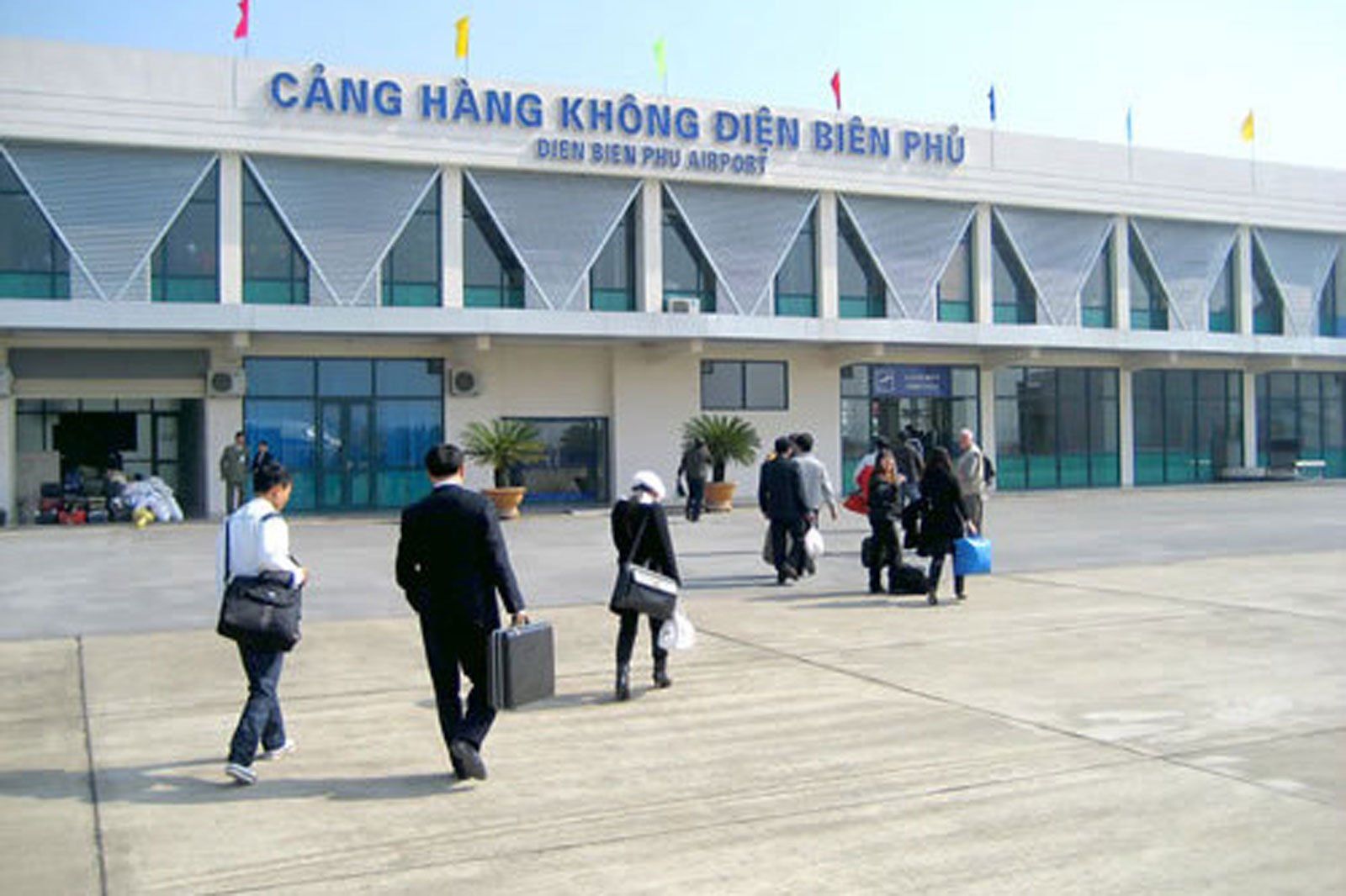 A group of people walking in front of an airport building