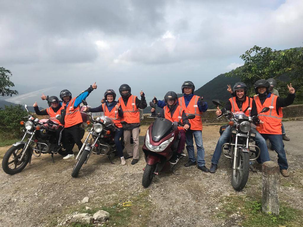 A group of people standing next to motorcycles and scooters.