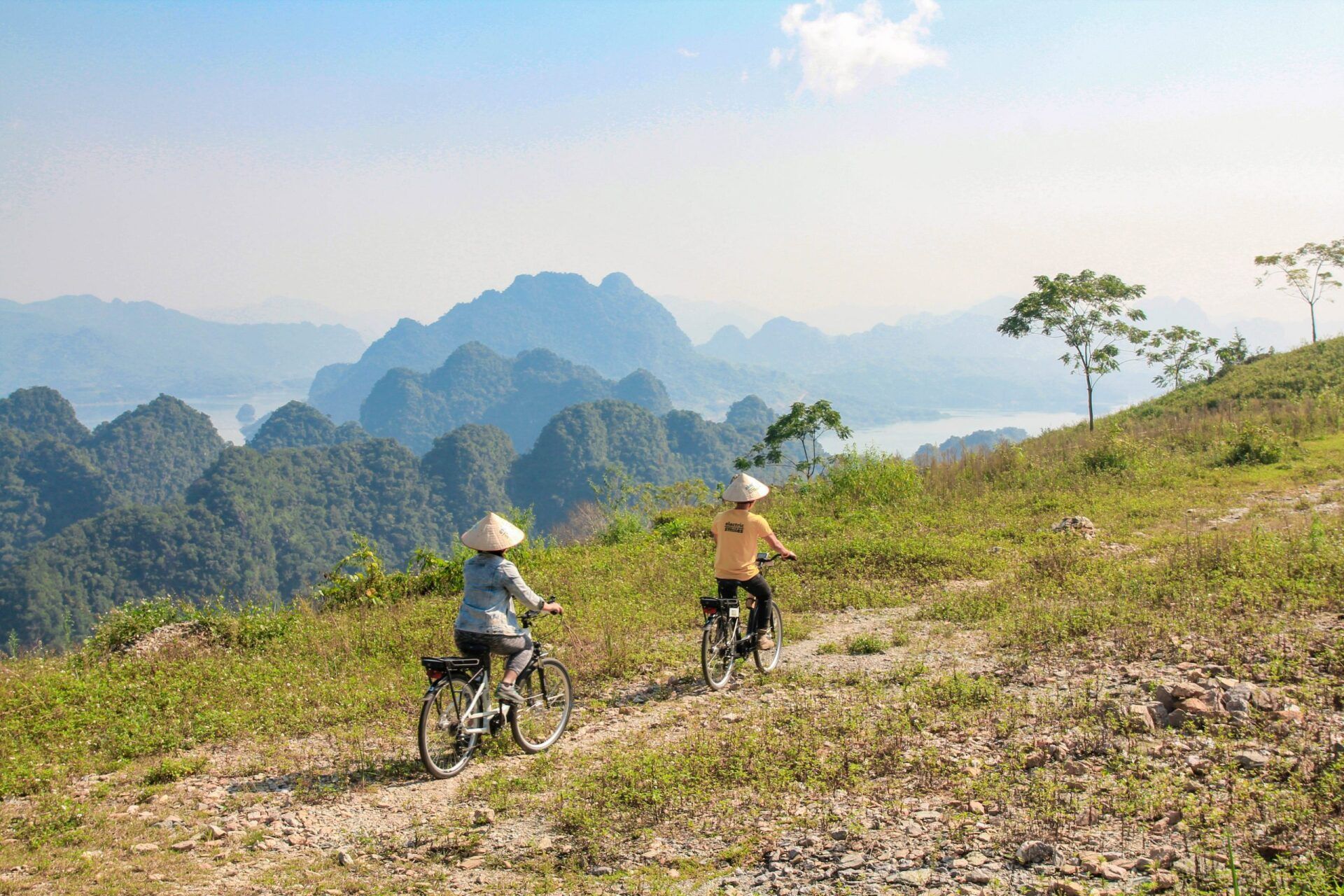 Two people are riding bicycles on a dirt road in the mountains.