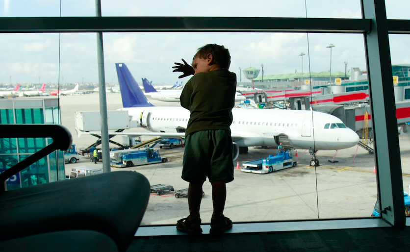 A little boy looking out a window at an airport