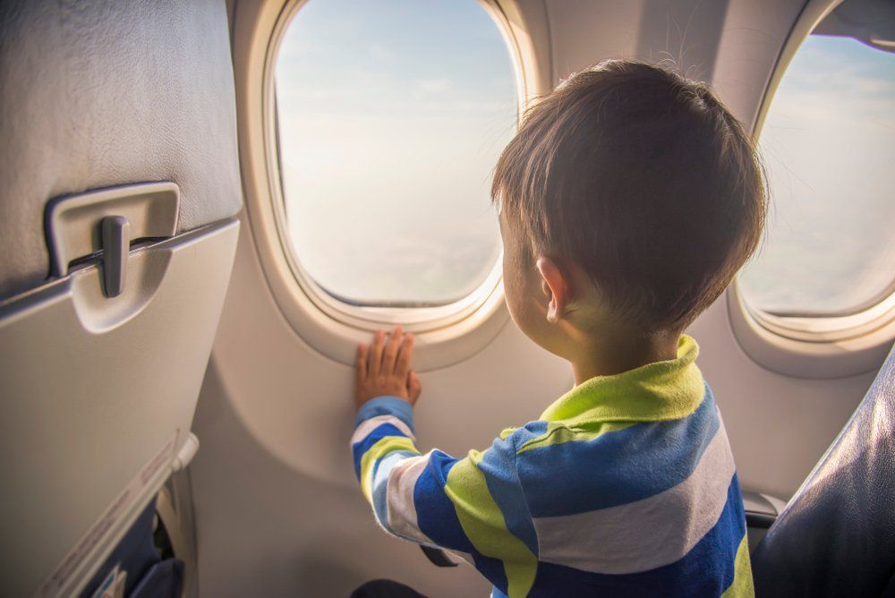 A young boy is looking out of an airplane window.
