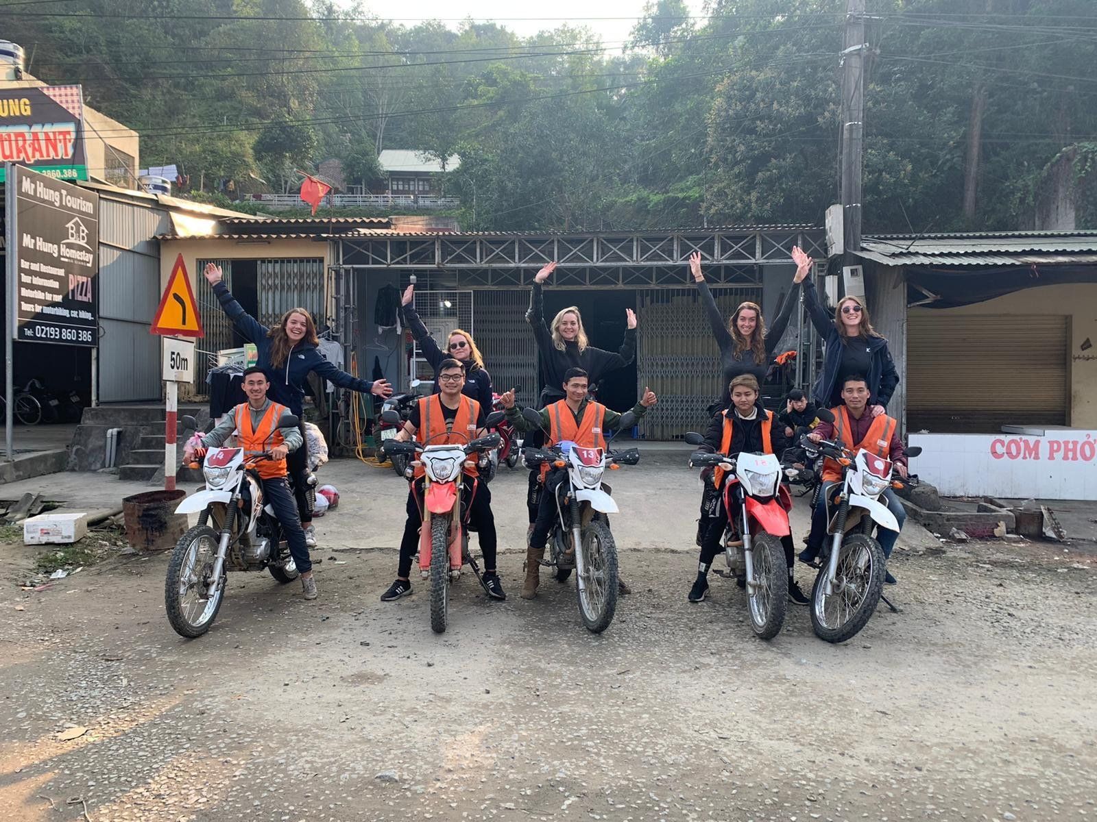 A group of people standing next to each other on motorcycles.